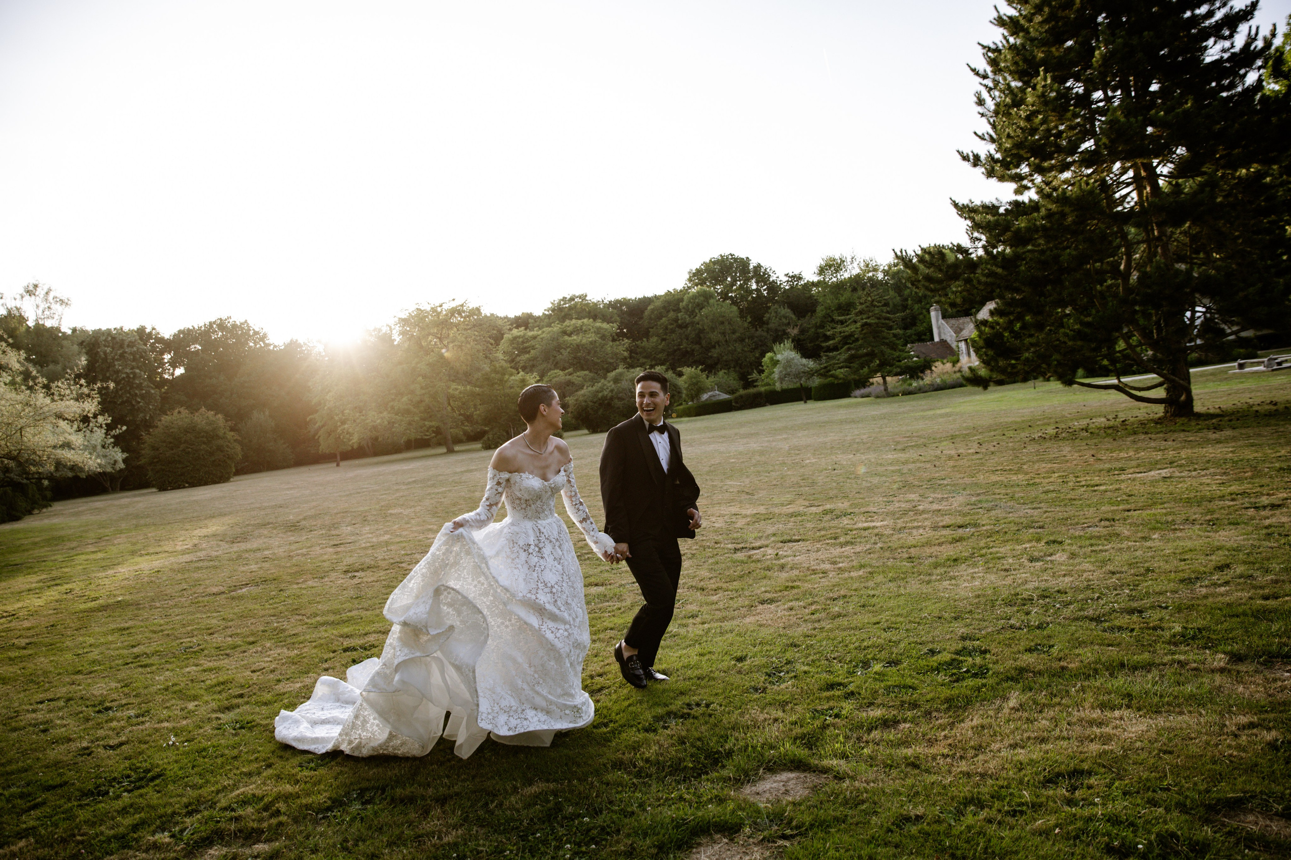 Bride and groom walking hand in hand at sunset on the grounds of a French château, romantic destination wedding photography in France