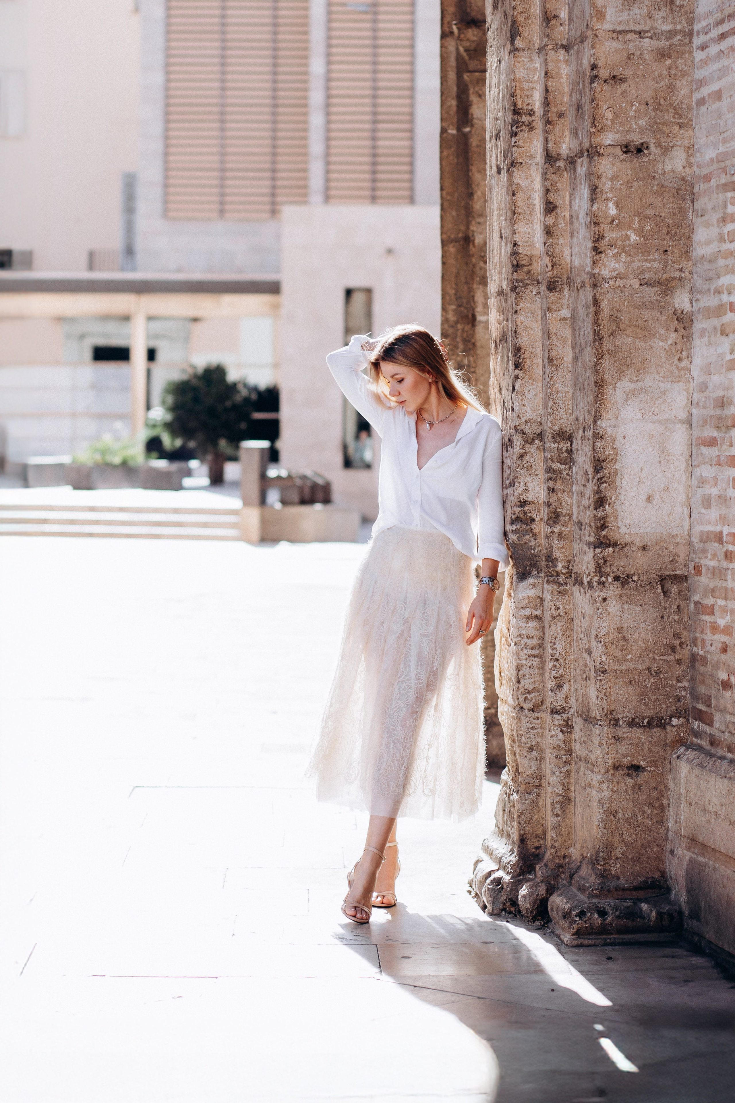 Элегантный женский портрет, снятый при естественном освещении у исторической каменной стены в Валенсии, Испания — идеально подходит для демонстрации вневременной и женственной портретной фотографии для женщин, ищущих профессиональные фотосессии в Валенсии и по всей Испании.