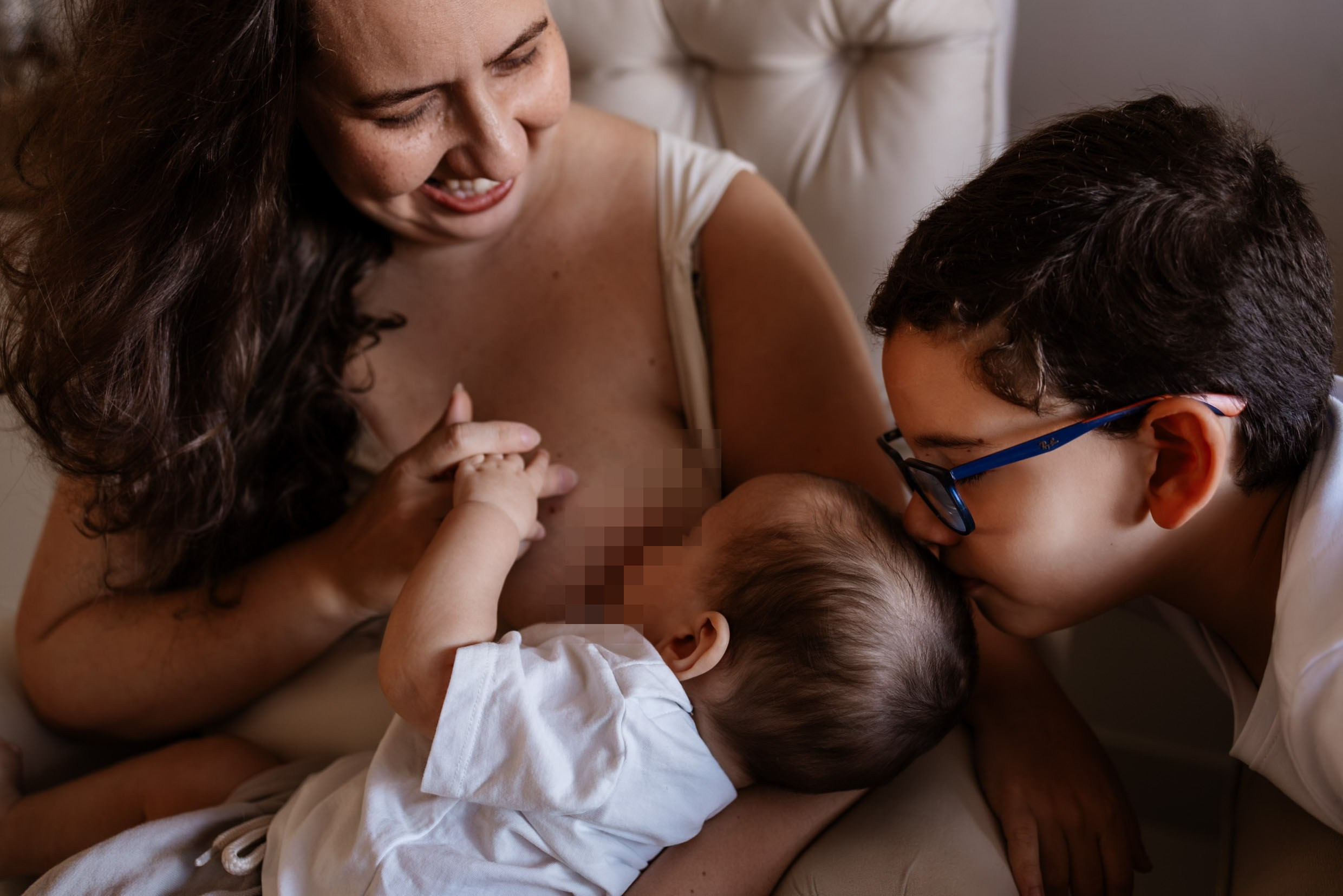 Irmão beija bebê enquanto ele é amamentado