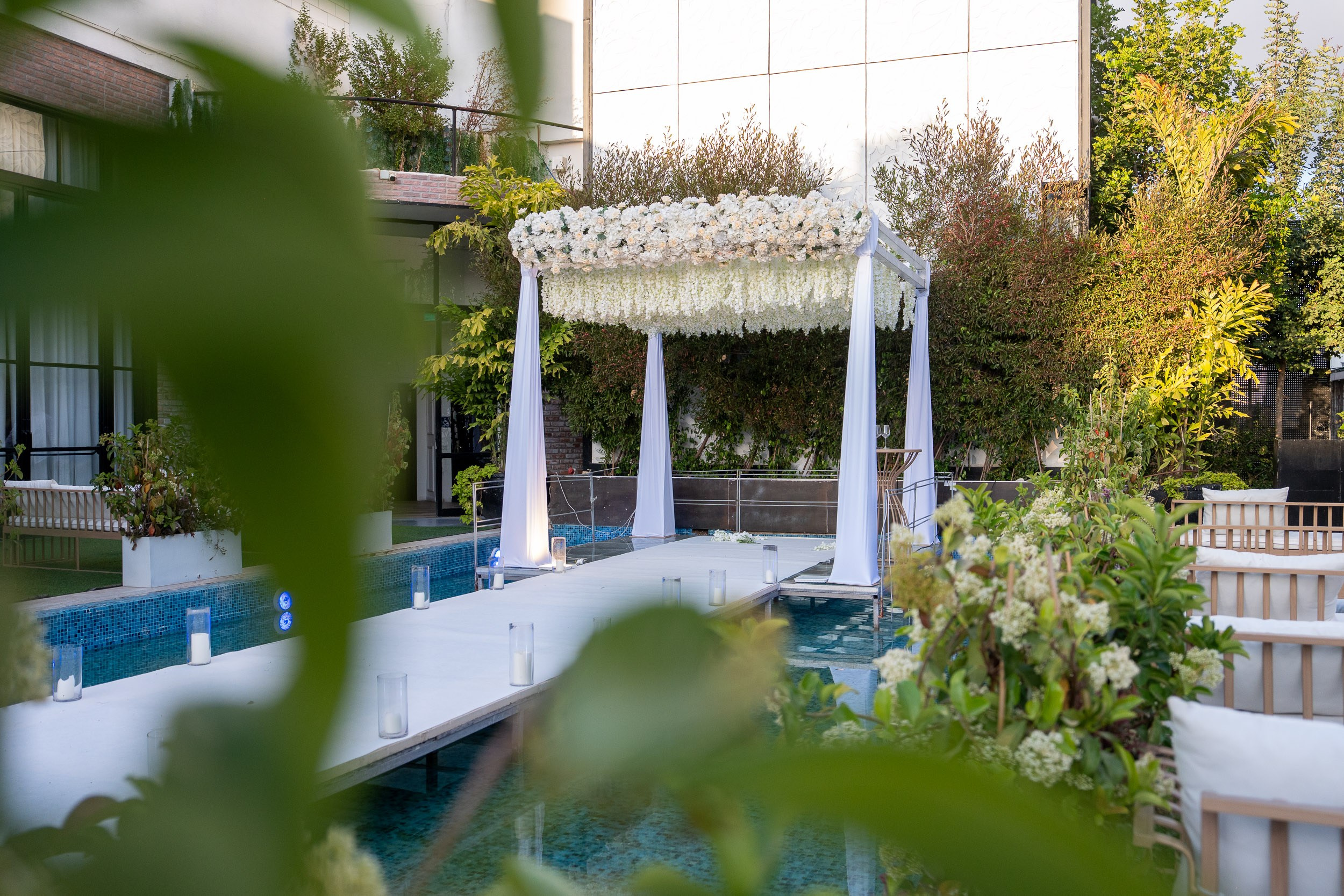 Elegant white flower Chuppah and an aisle over a swimming pool at Kadita Event Garden in Emek Hefer, Israel