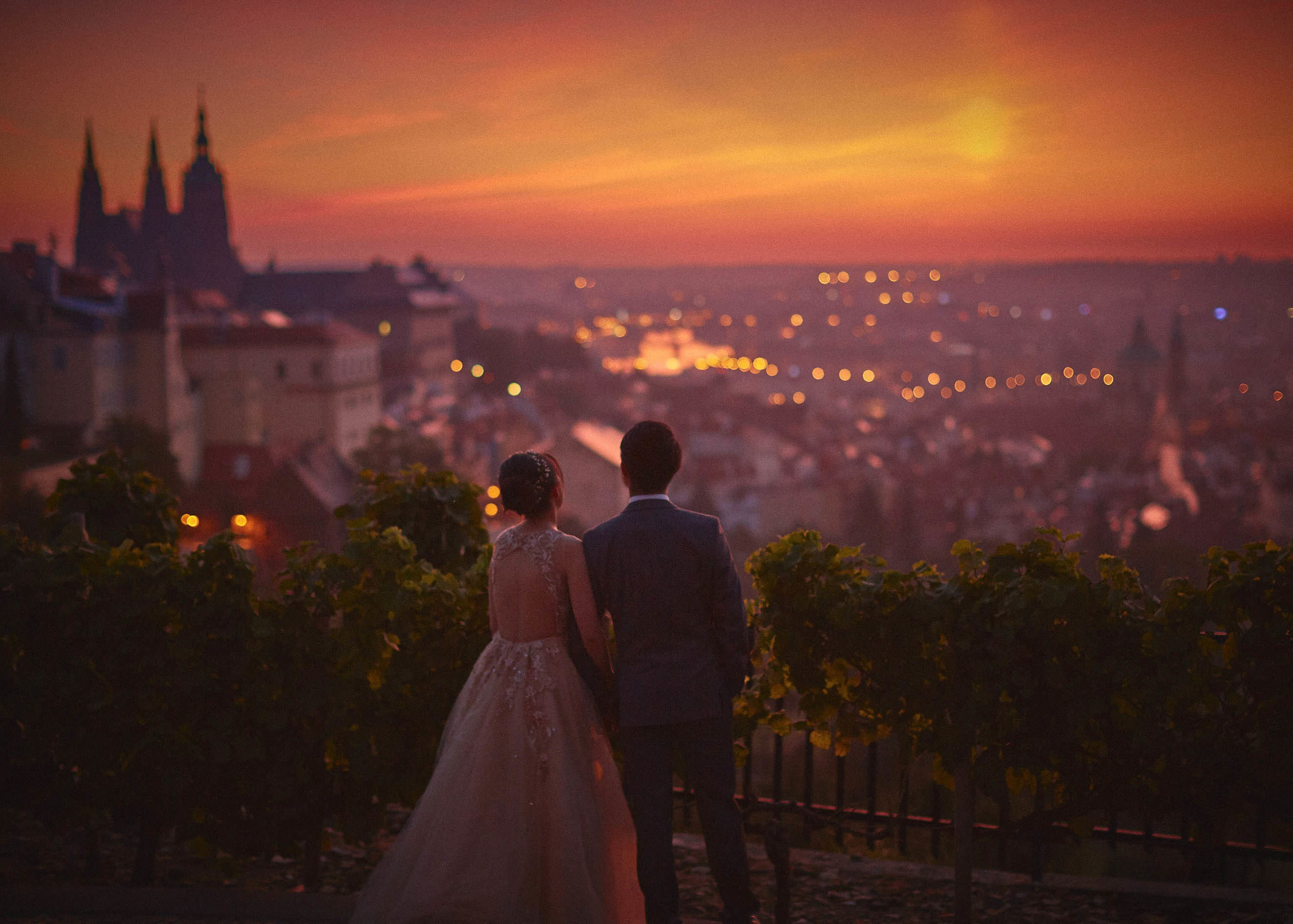 Couple watch the early morning sunrise above the city of Prague in a vineyard