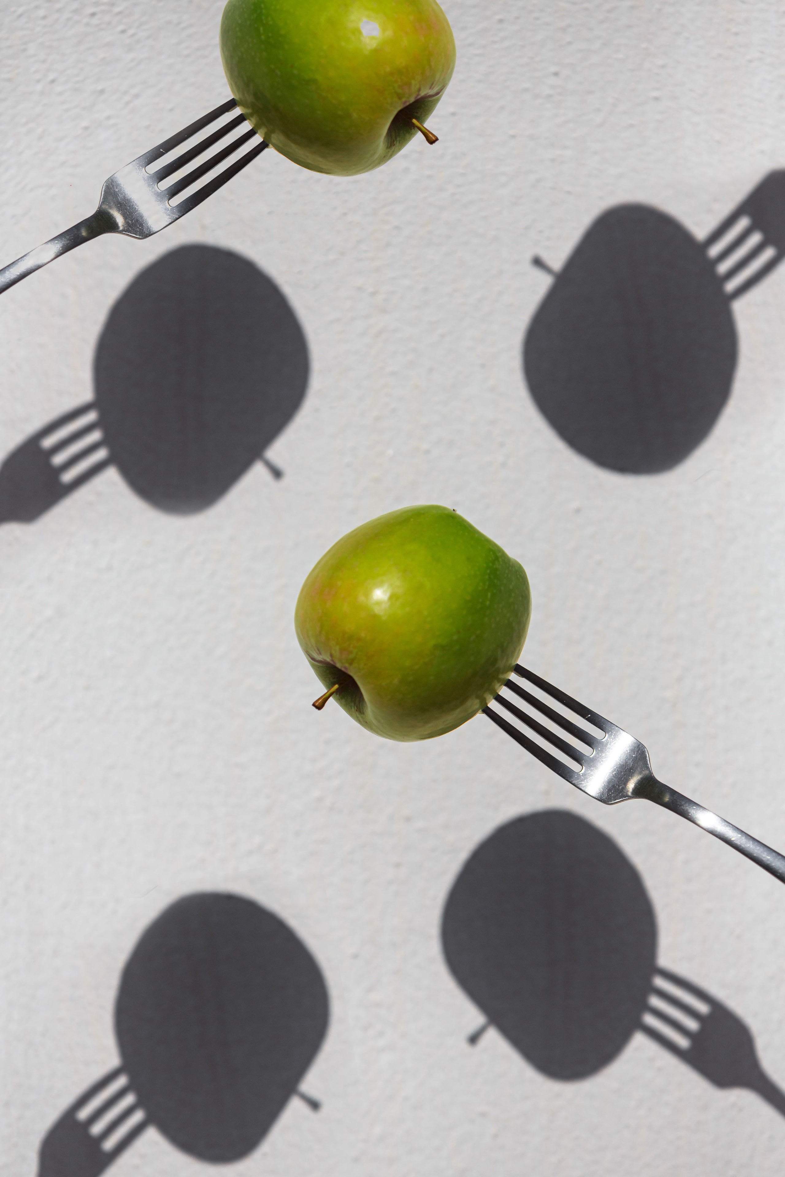 manzana pinchada con un tenedor con sombras nítidas