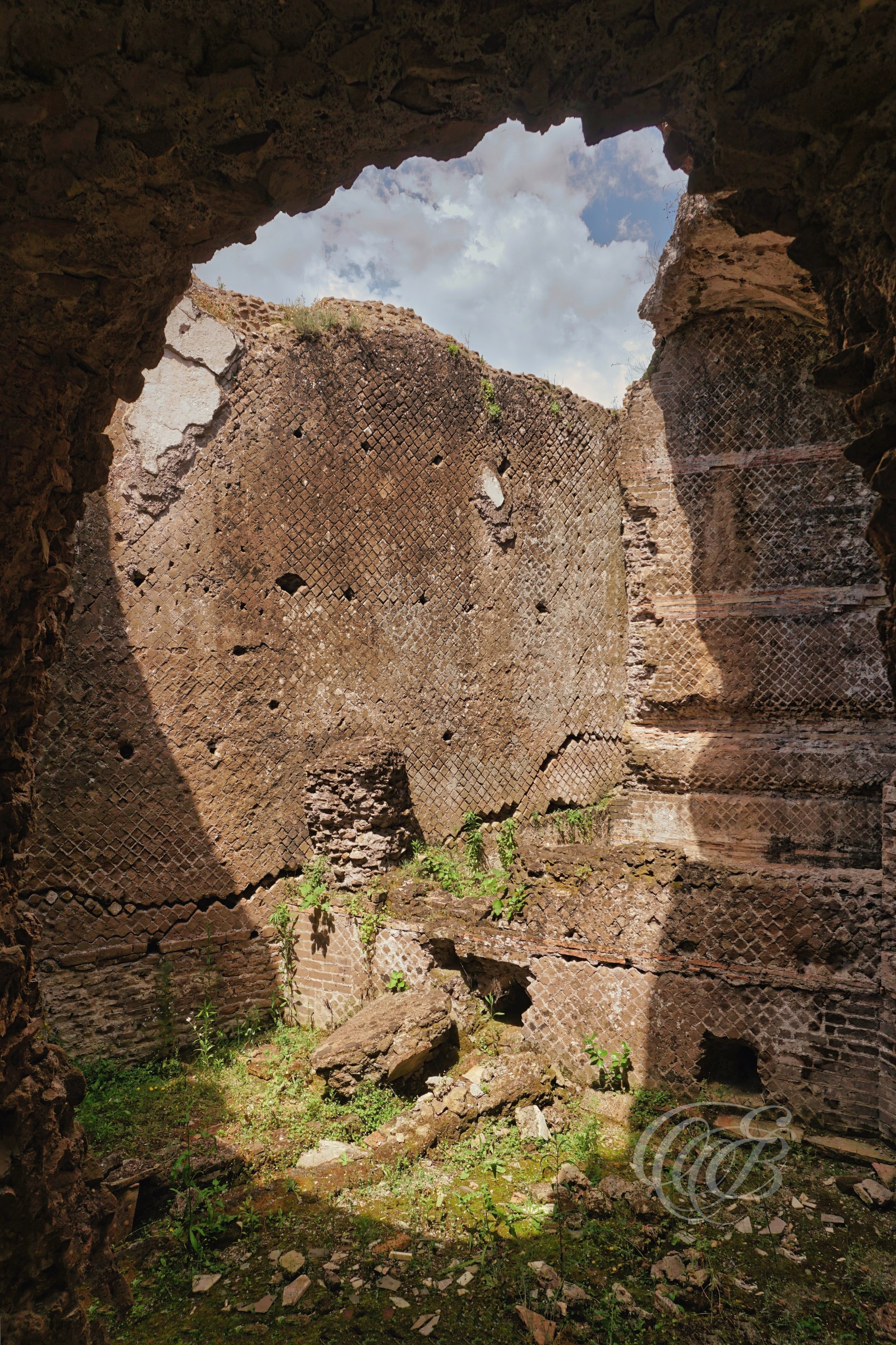 A view from beneath a collapsed section of the Small Thermae reveals the surviving brickwork and vaulted construction of the Roman baths. The open ceiling allows natural light to enter the ruins, highlighting the textures and craftsmanship that have endured for nearly two millennia.