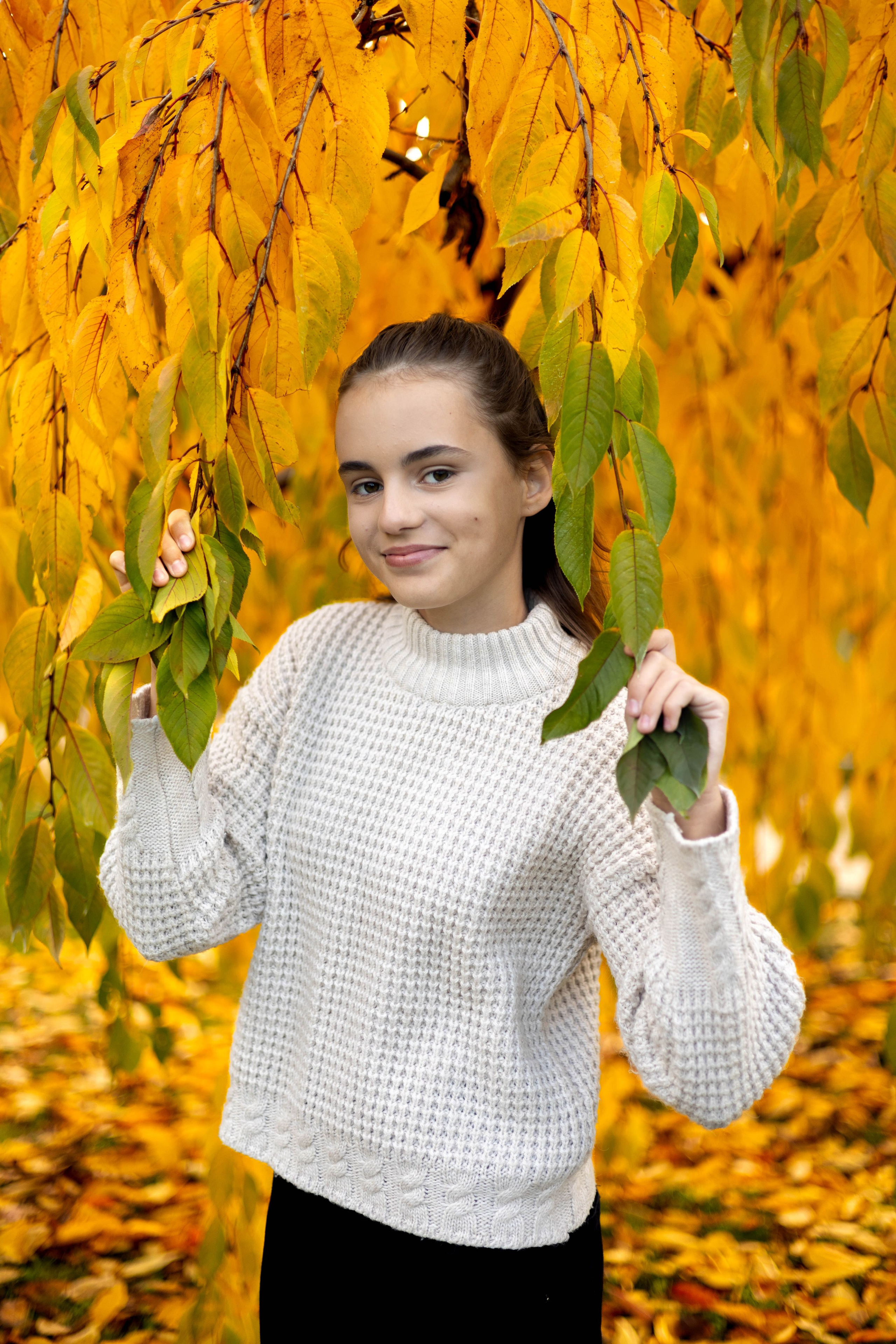 Девушка в осеннем парке позирует среди золотых листьев.