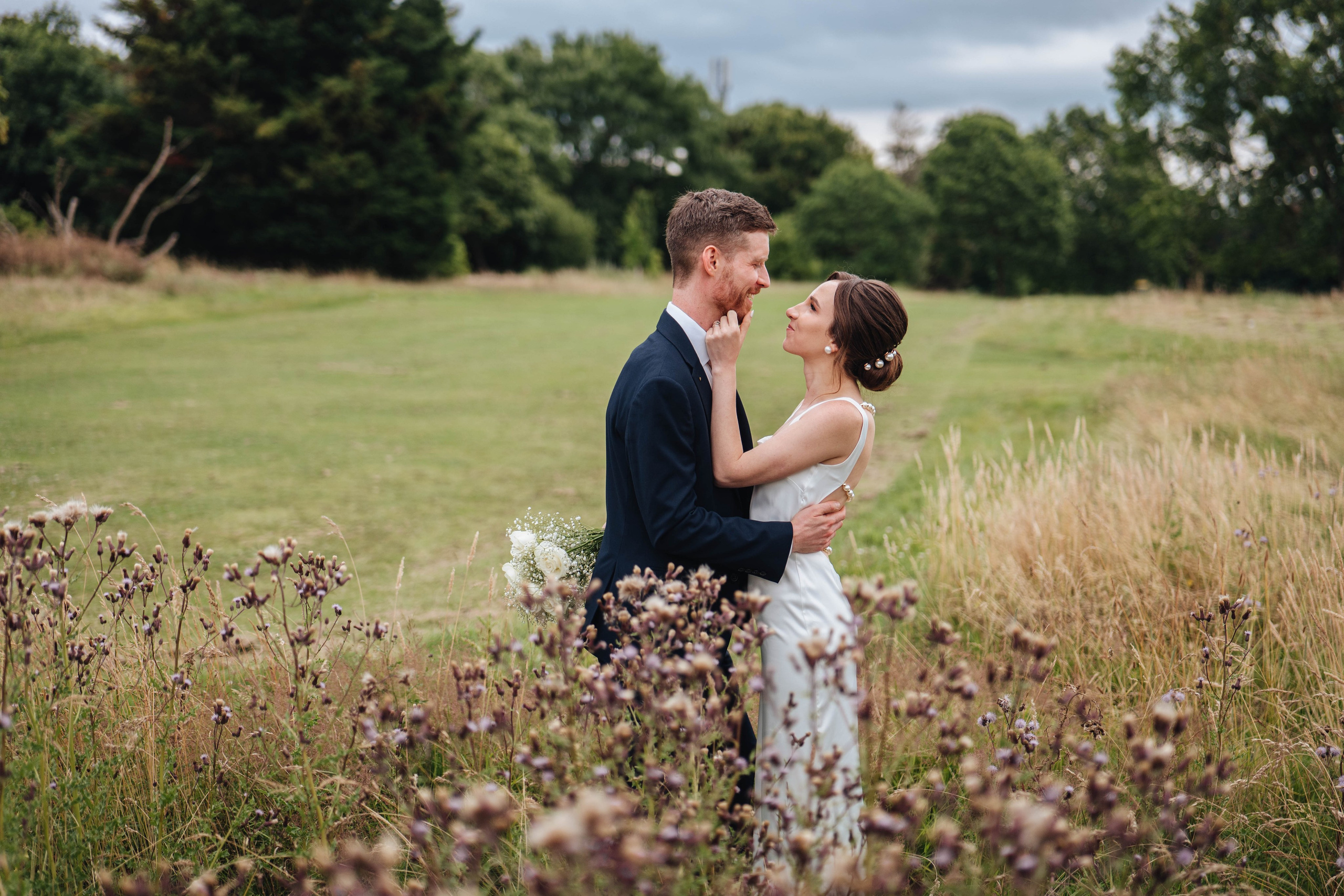 moody photo of bride and groom are looking at each other in fields