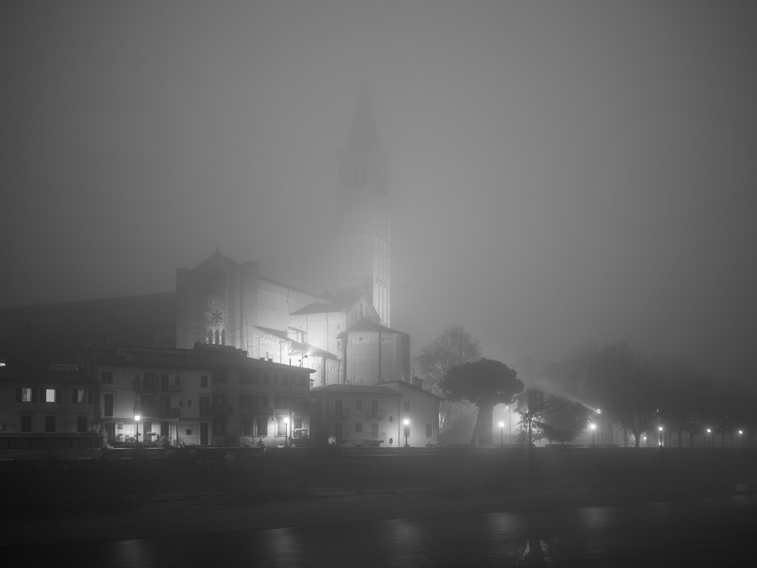 Historic Verona emerging through winter fog. A black and white architectural fine art photograph capturing silence, depth and the passage of time.