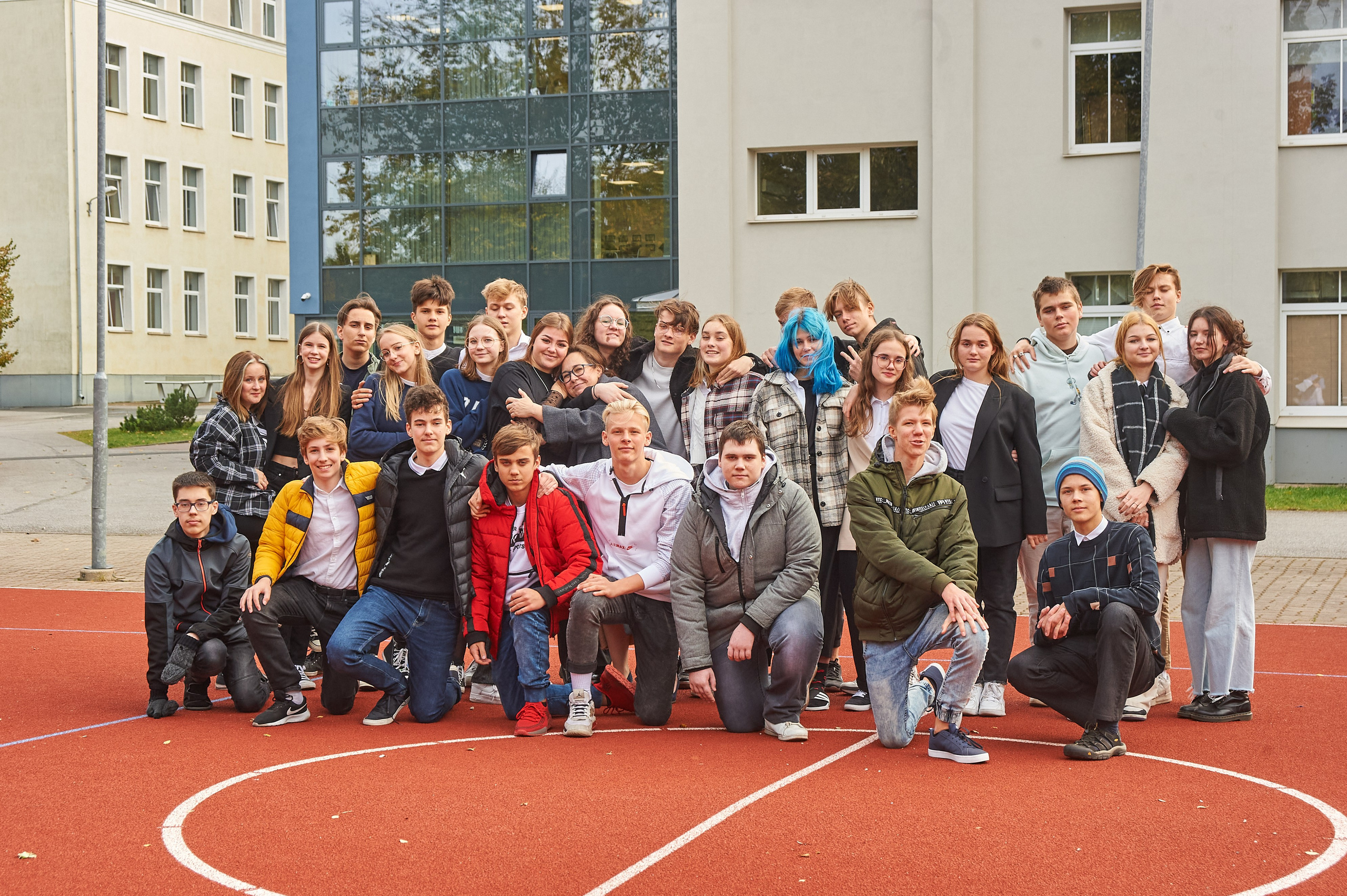 Дети обнимаются и улыбаются на фоне школы