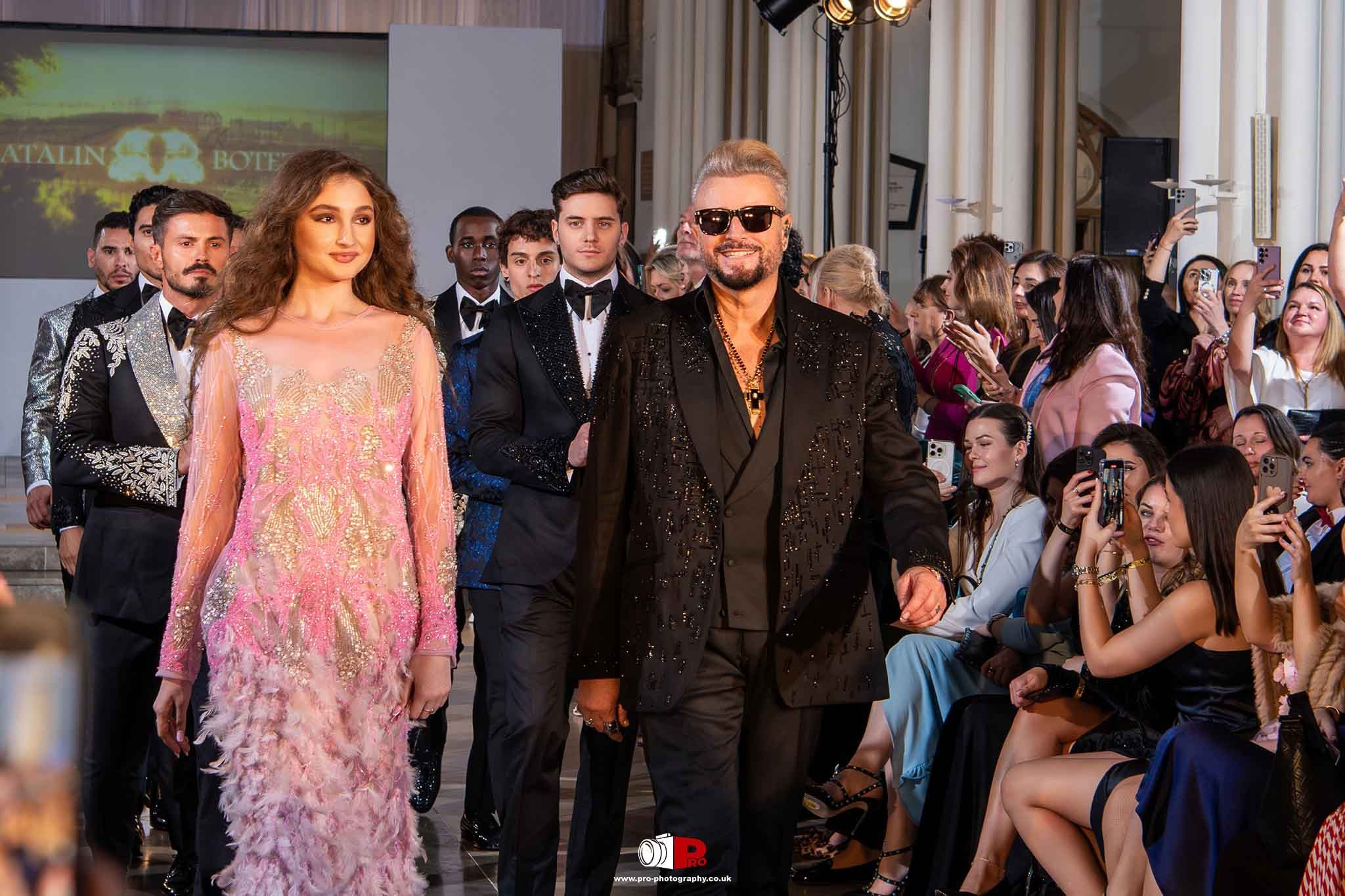 Models walking the runway at a glamorous fashion show, featuring designer outfits and an enthusiastic audience, capturing the moment.