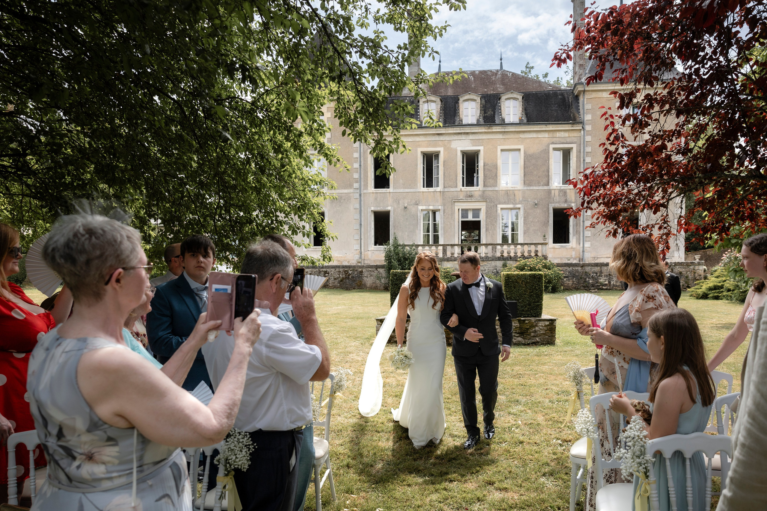 Bride and groom walking back down the aisle as their guests photograph them