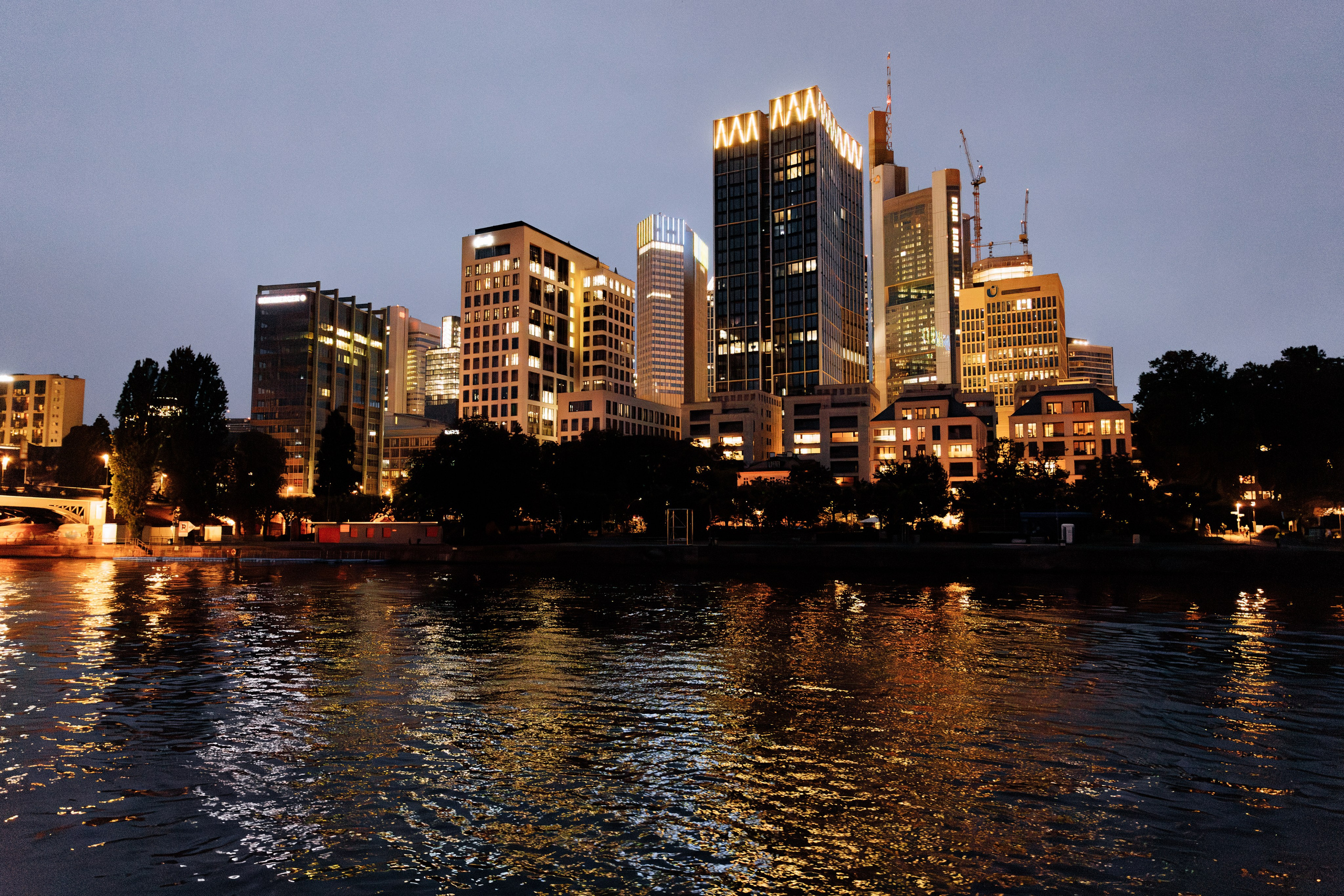 Blick auf das nächtliche Frankfurt vom Wasser aus. Die Lichter der Stadt spiegeln sich im Fluss und schaffen eine beeindruckende Atmosphäre.