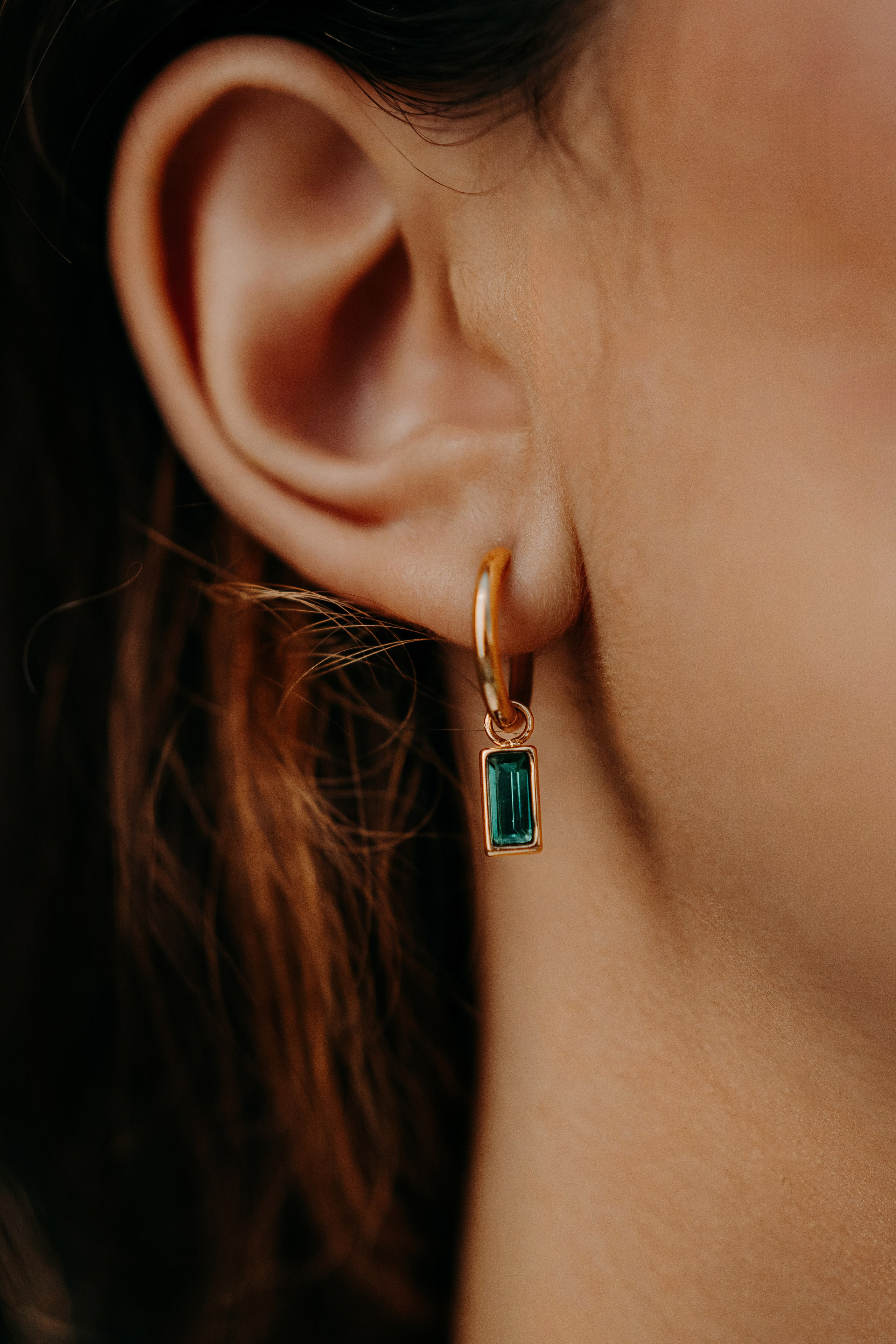 Close-up of emerald earrings paired with sleek hair, highlighting a modern jewelry trend.