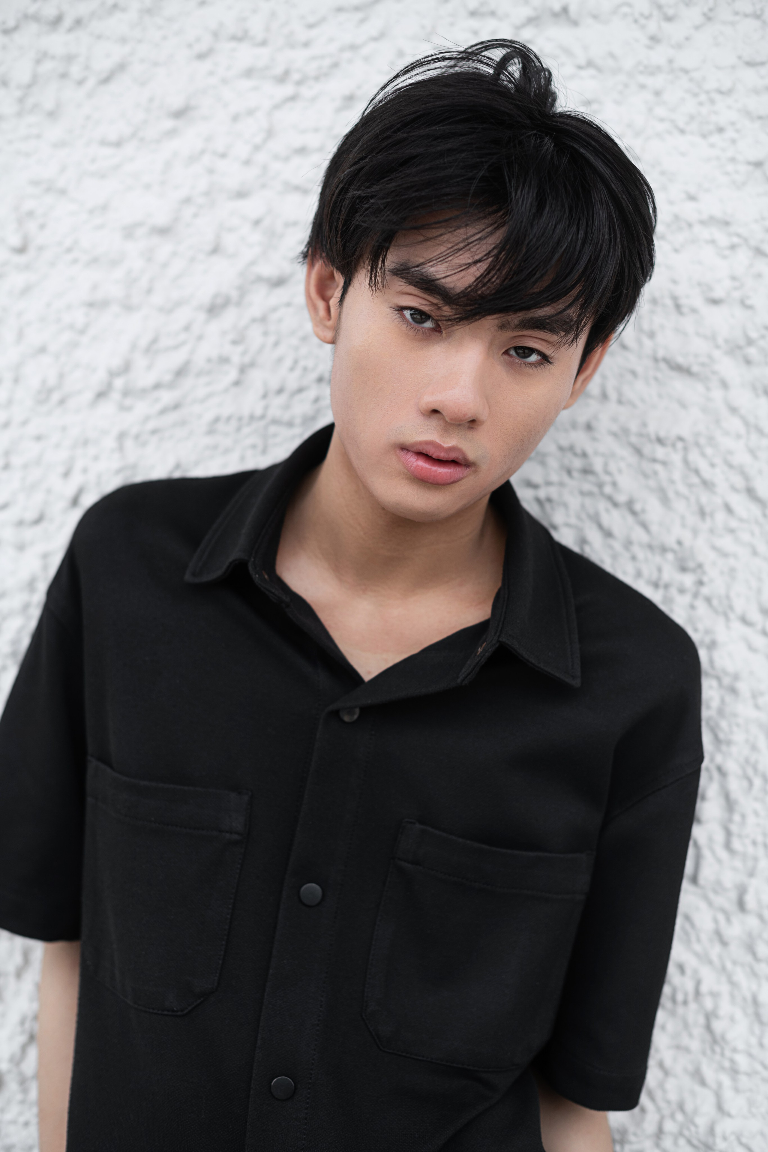 Sophisticated portrait of a male model in a stylish outfit with natural light and detailed textures in an elegant Singapore setting.