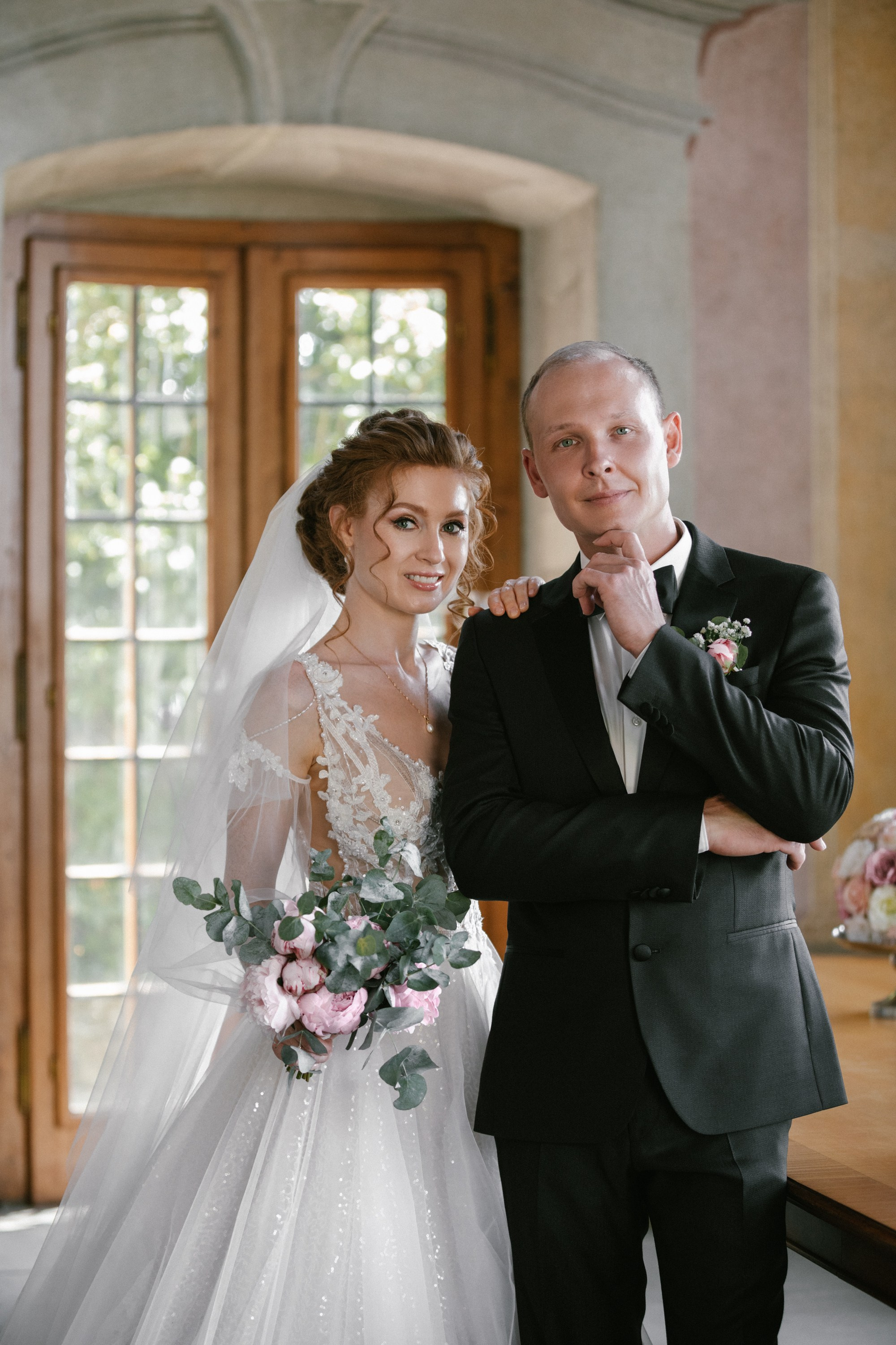 Brautpaar posiert lächelnd mit Bouquet im Teehaus Schloss Meersburg