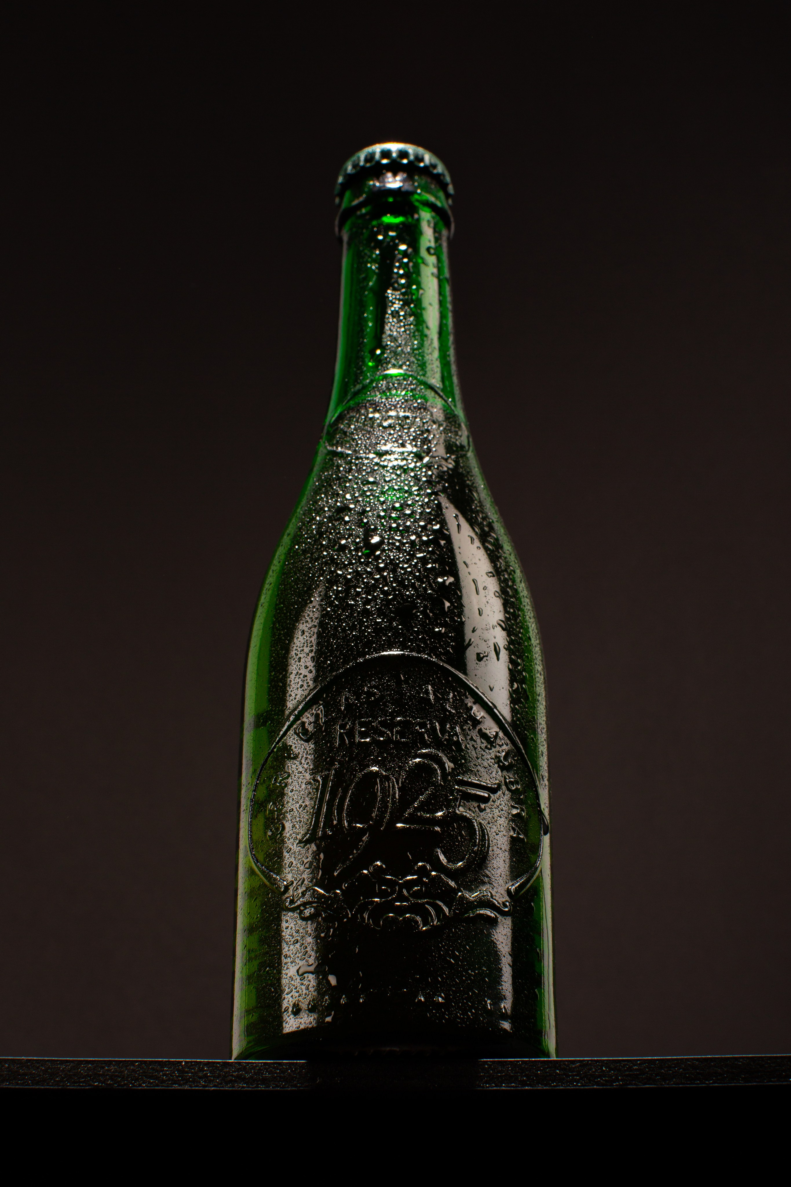 botella verde con gotas fondo oscuro fotografía de producto