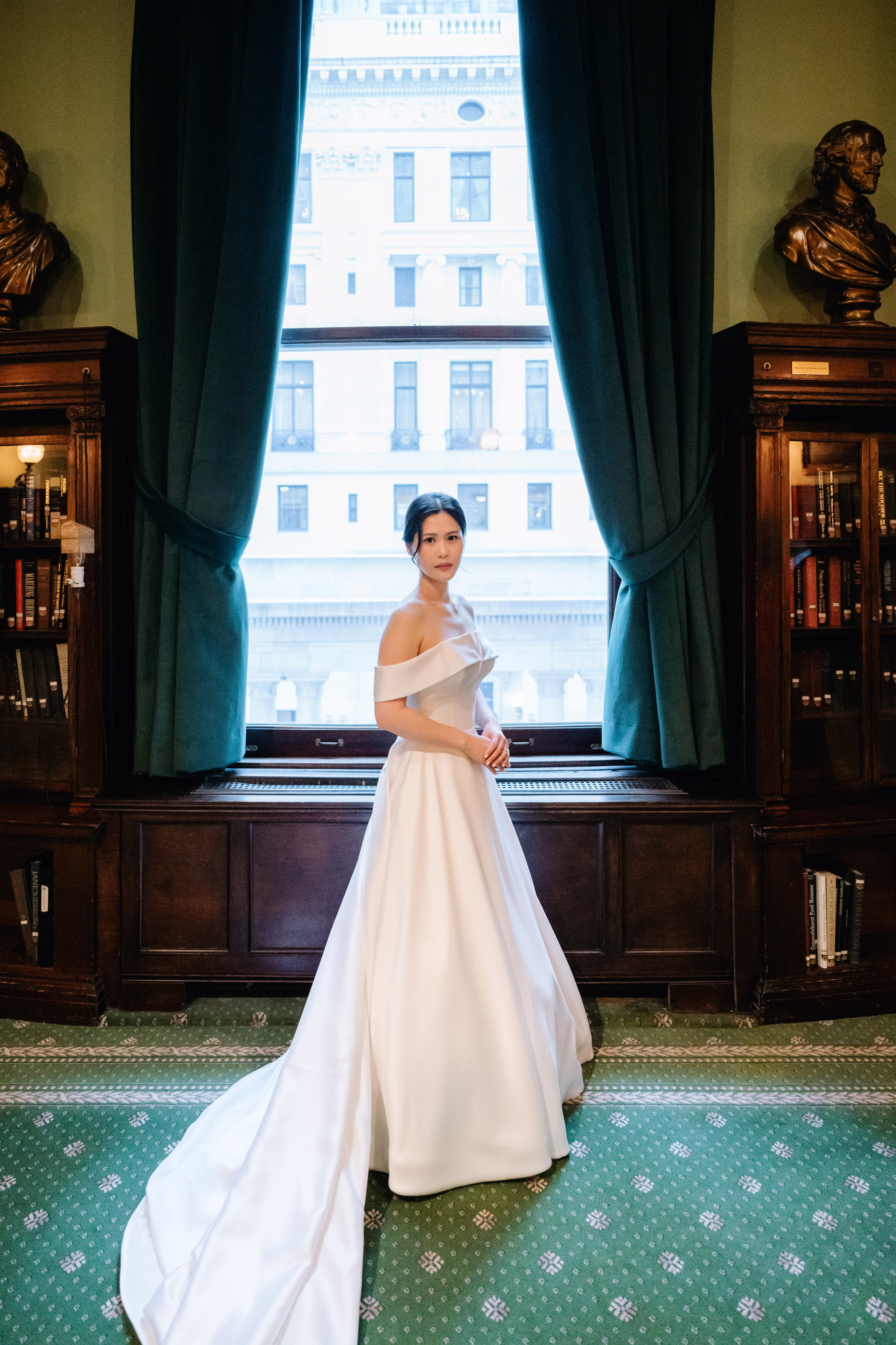 a woman in a wedding dress standing in front of a window
