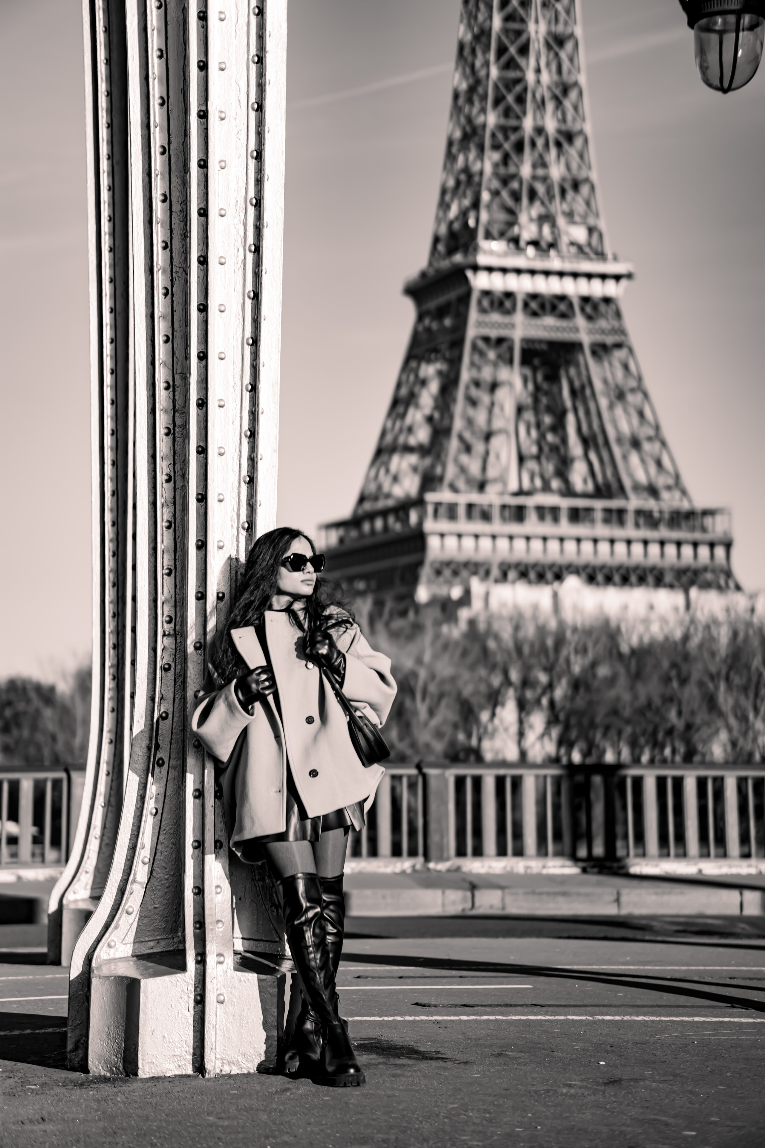  a woman leaning on bir hakim bridge and standing with eiffel tower view behind her