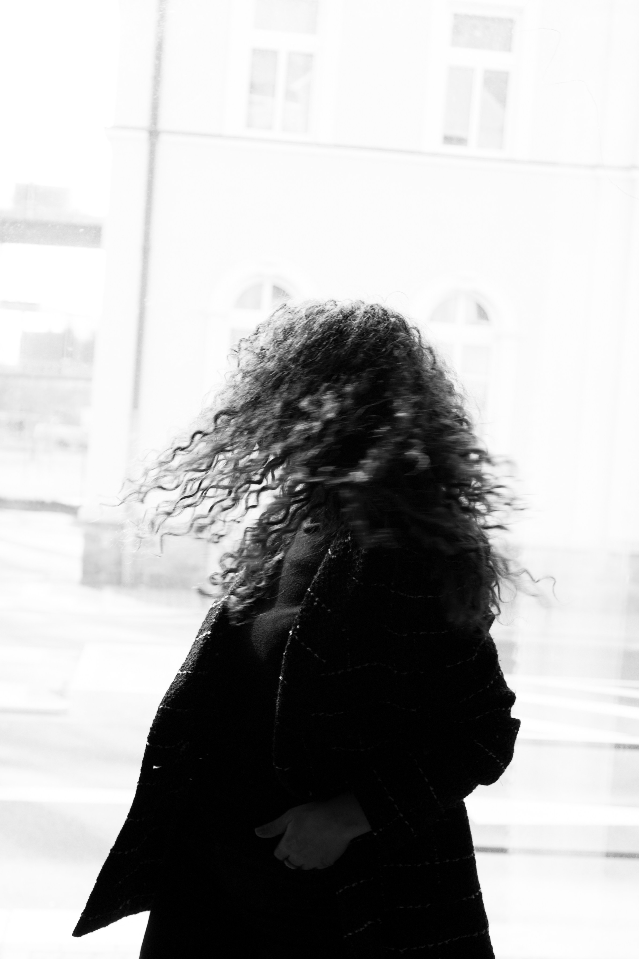 Schwarz-Weiß, Haare im Wind vor Fensterlicht – dynamisches, kreatives Portrait
