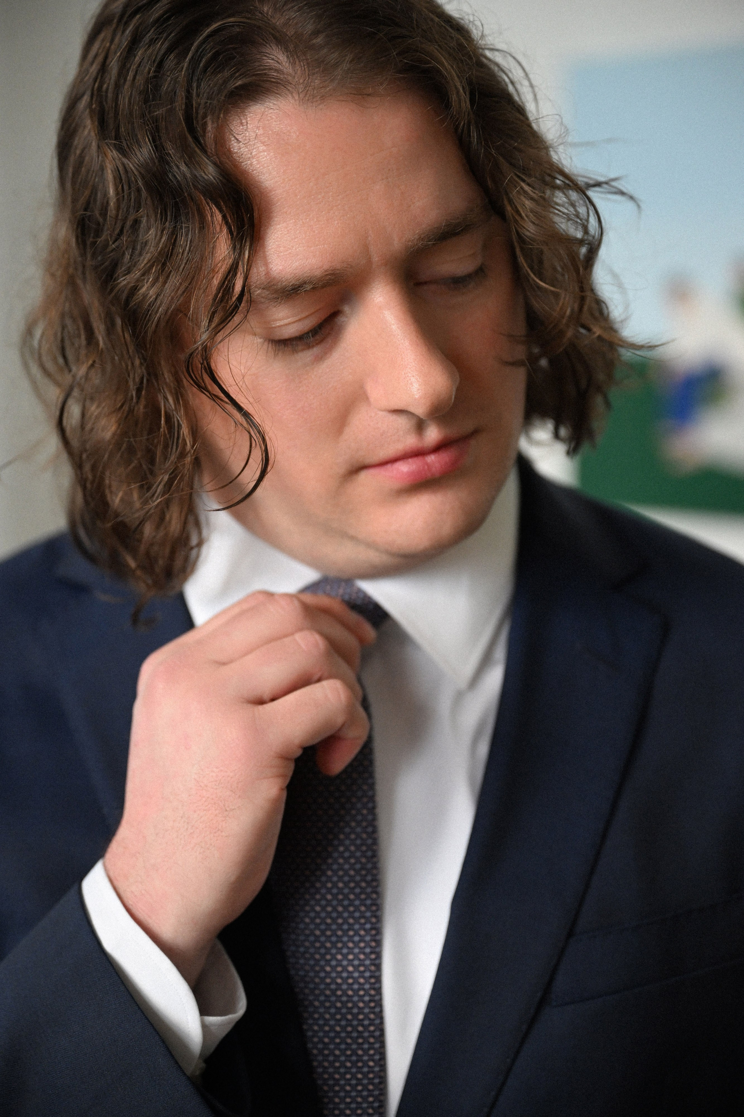 a man in a suit tying his tie