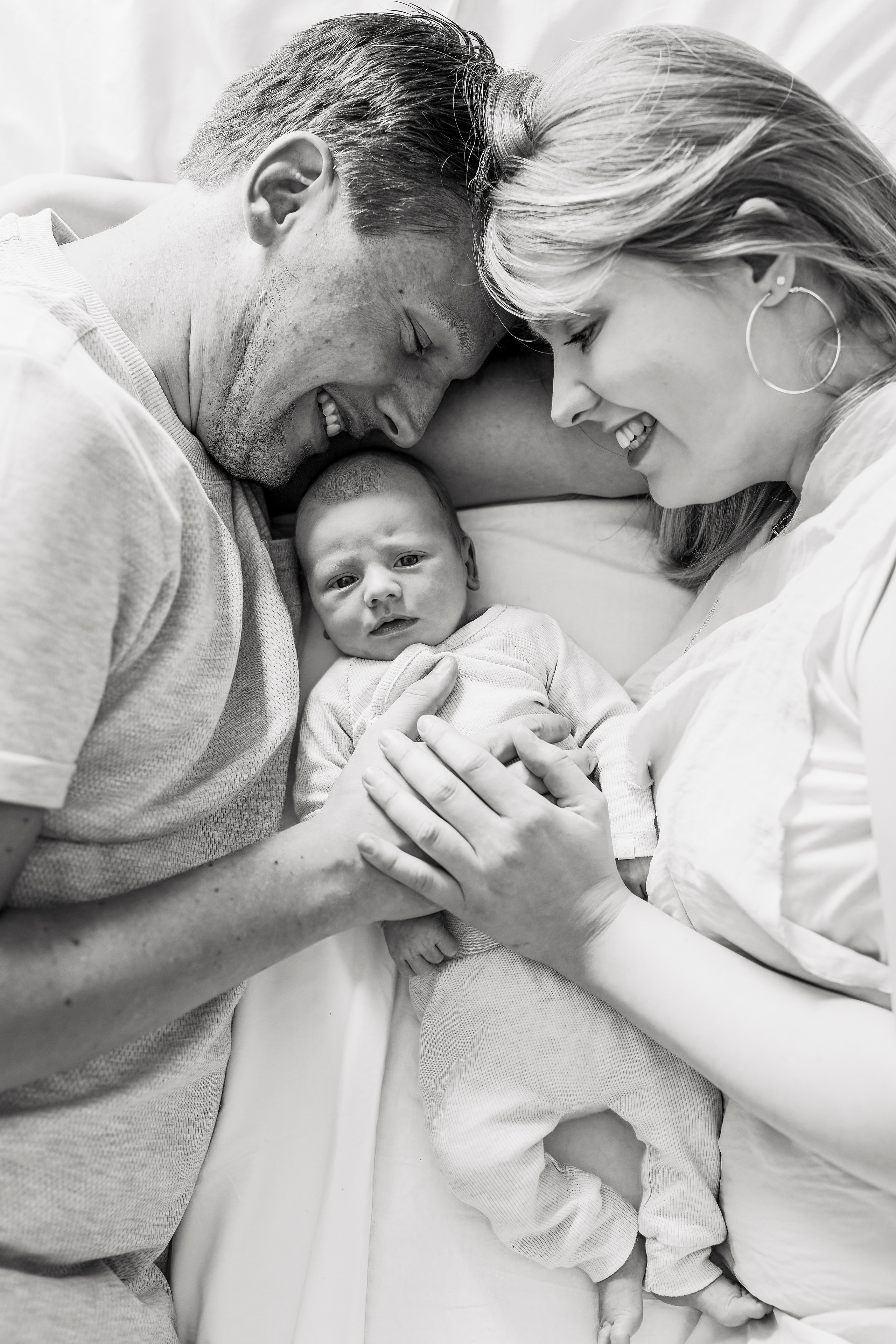 Thuis op bed, een warm moment tussen ouders en hun pasgeboren kindje.
