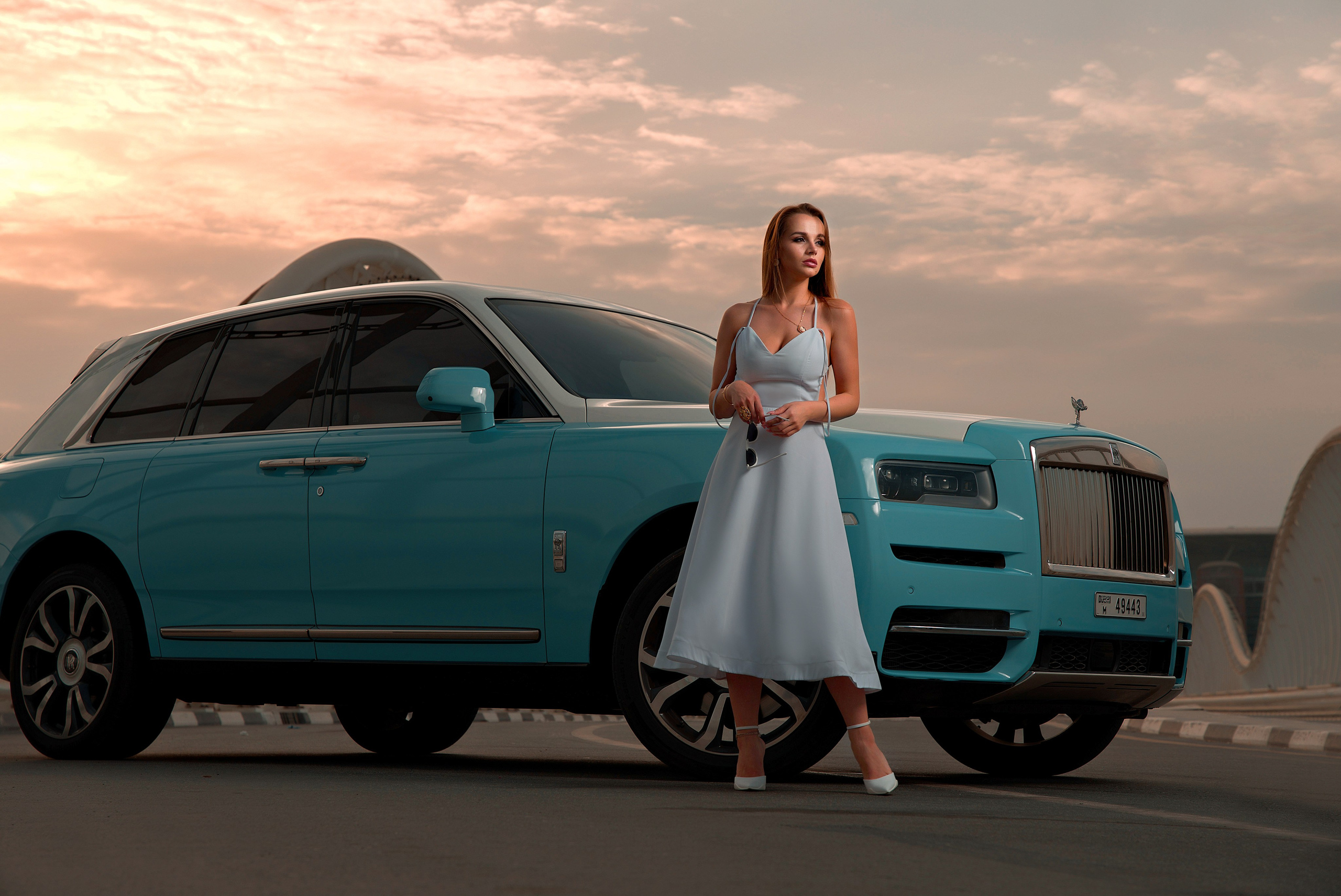 A beautiful woman sits inside a stunning red car with an open sunroof, set against the backdrop of a closed Dubai road