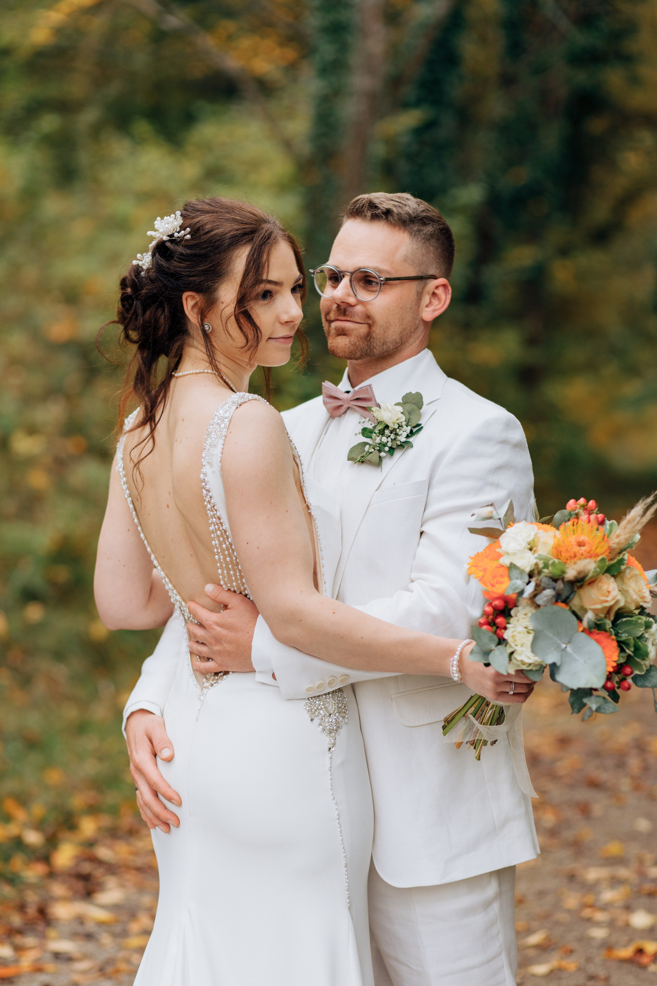 Der Bräutigam schaut verliebt auf die schöne Braut und umarmt sie liebevoll an der Taille.