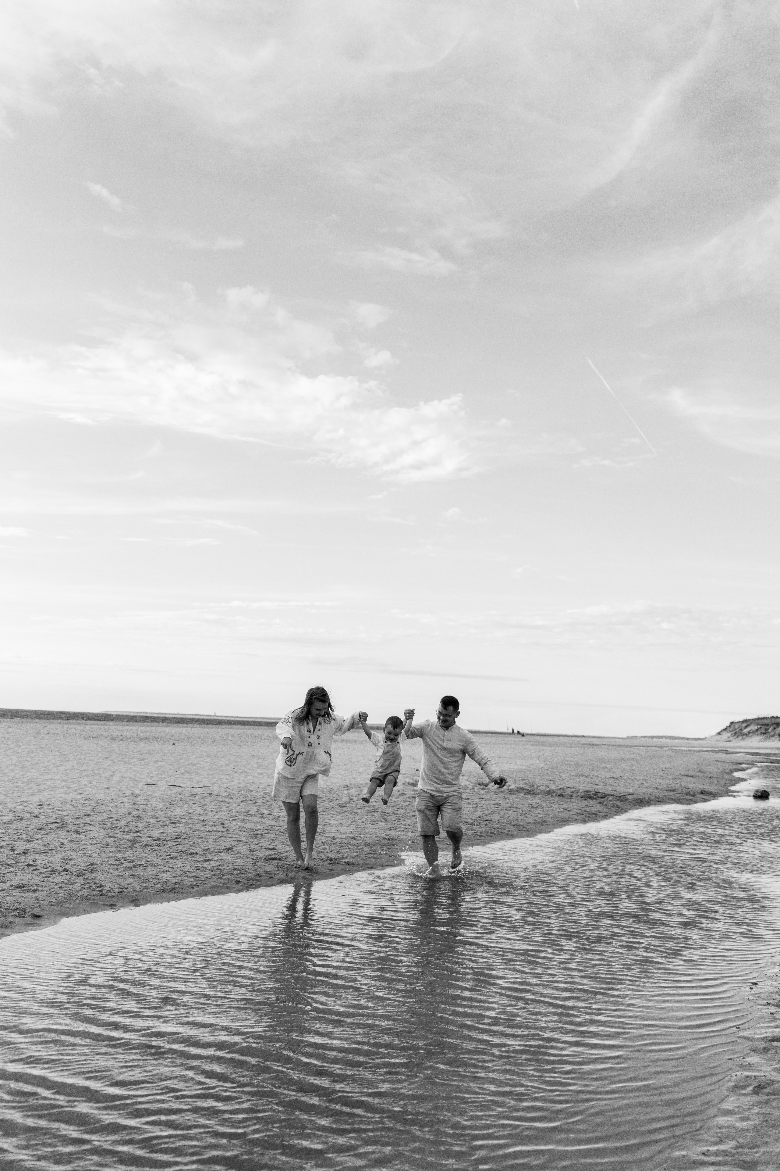 Black and white photo of parents holding child's hand