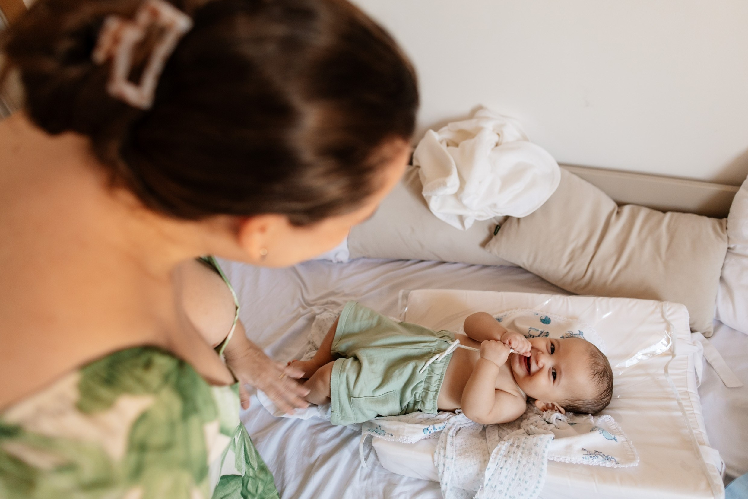 Mãe observa o bebê em momento espontâneo da rotina.