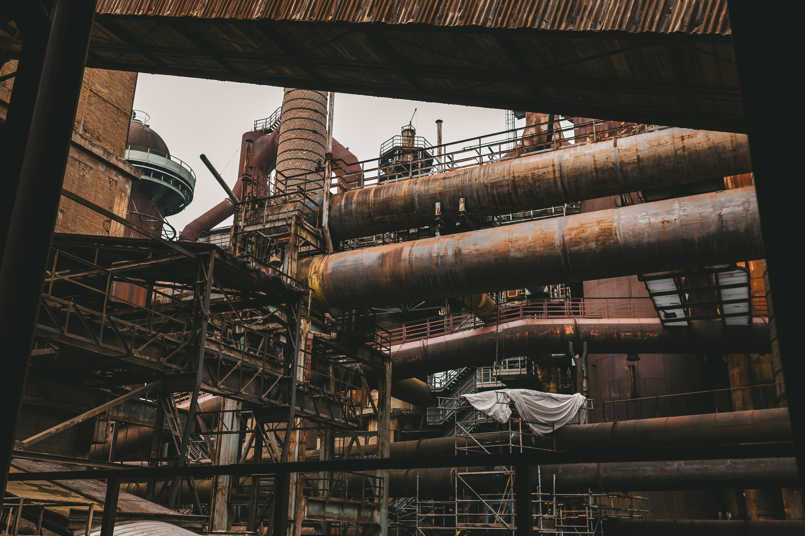 Силуэт доменной печи и труб на фоне светлого неба.