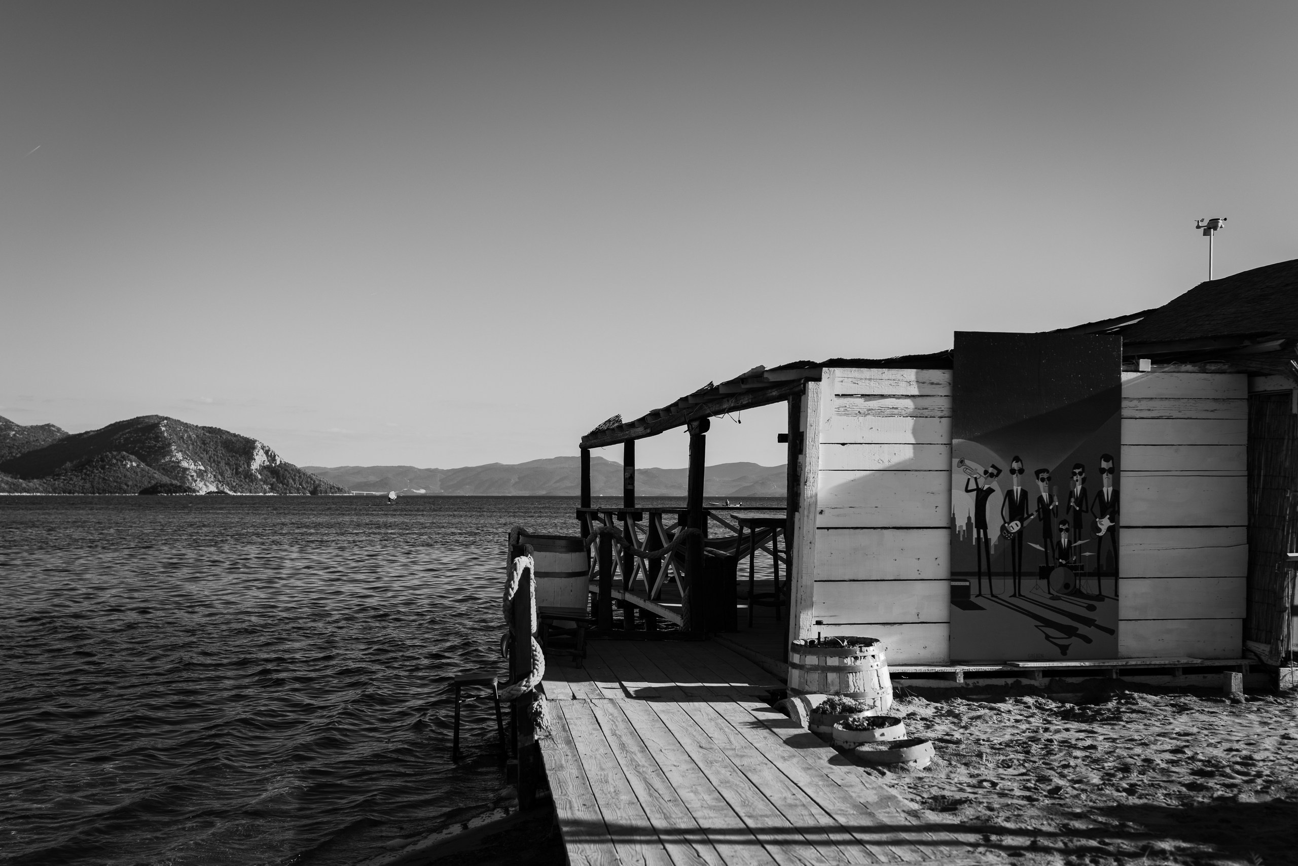 Crno-bijela autorska fotografija stare drvene kućice uz more na području delte Neretve