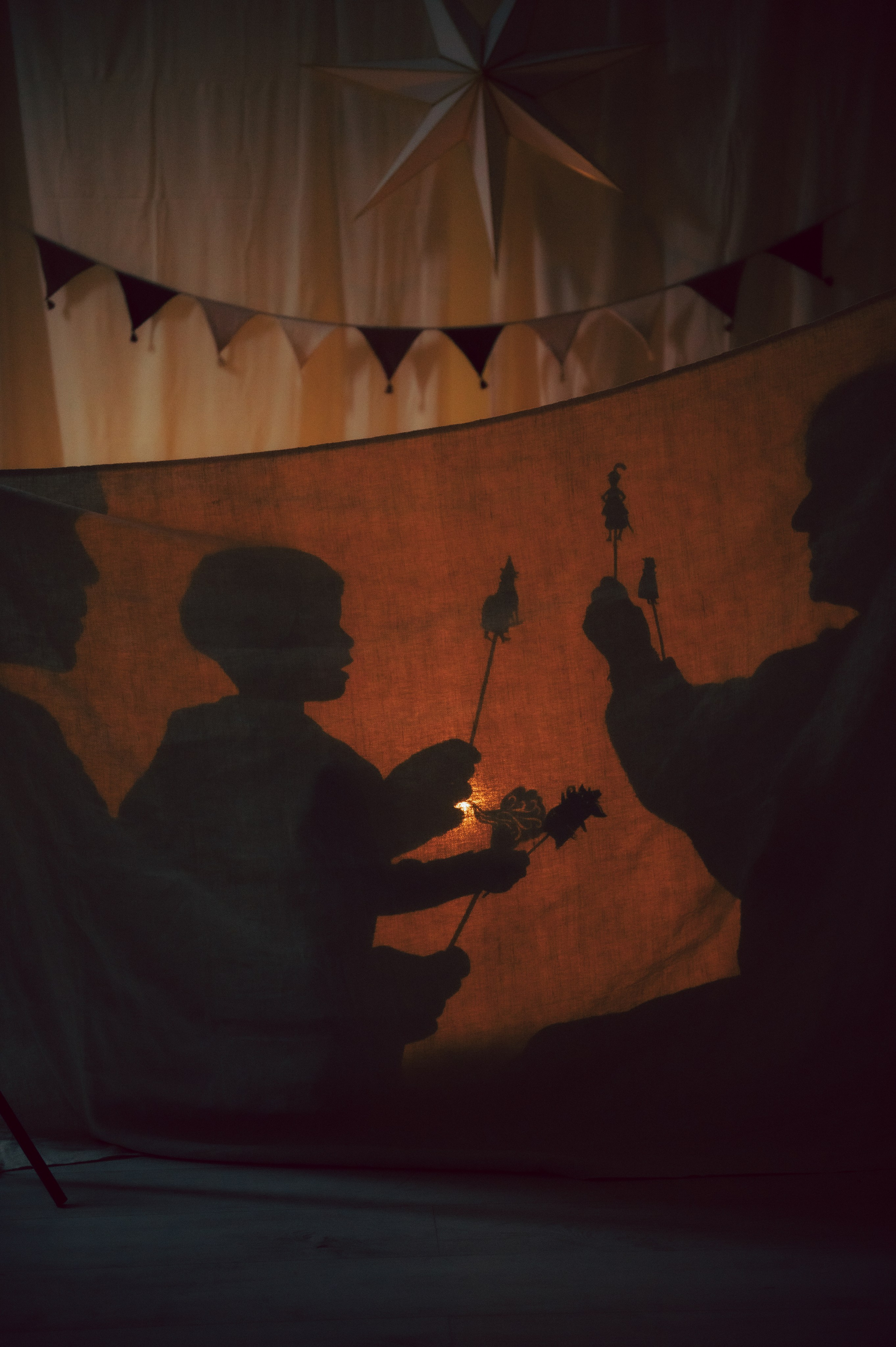 A heartwarming Christmas shadow play captured during a cozy family moment. Soft warm light reveals the silhouettes of parents and their child telling a festive story behind a curtain, creating an intimate and artistic holiday memory. Perfect inspiration for families looking to book a Christmas photoshoot in Milan with a lifestyle photographer who specializes in emotional, storytelling images. Christmas family photoshoot, shadow play photography, cozy holiday moments, storytelling family session, christmas lights aesthetic, lifestyle family photographer italy, winter photoshoot inspiration, intimate christmas photos, festive home session, parent child silhouettes, emotional family photography, milan photographer, anastasiia buchinskaia photographer, anamilanofoto