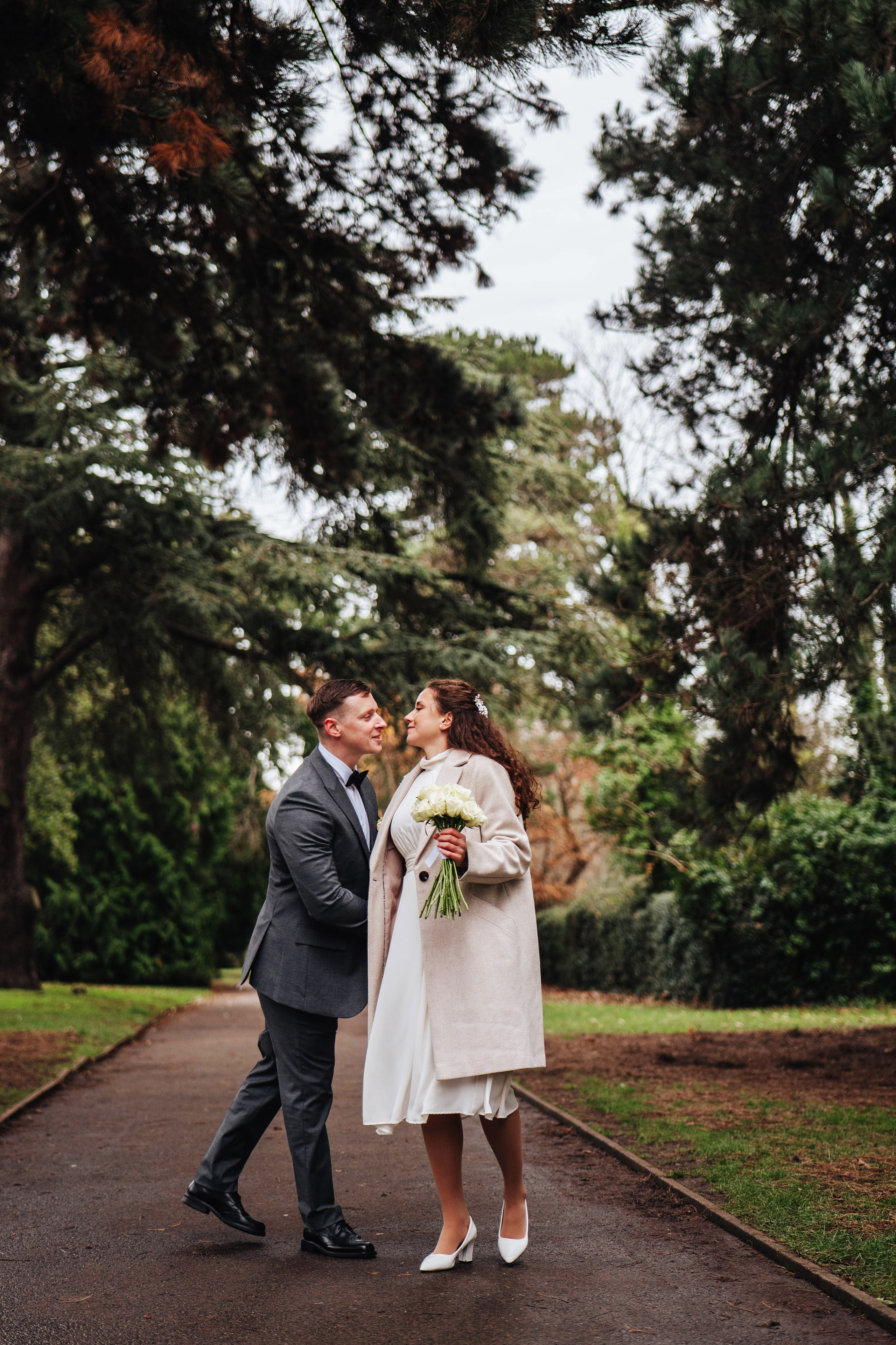 groom and bride walking down the path in the park