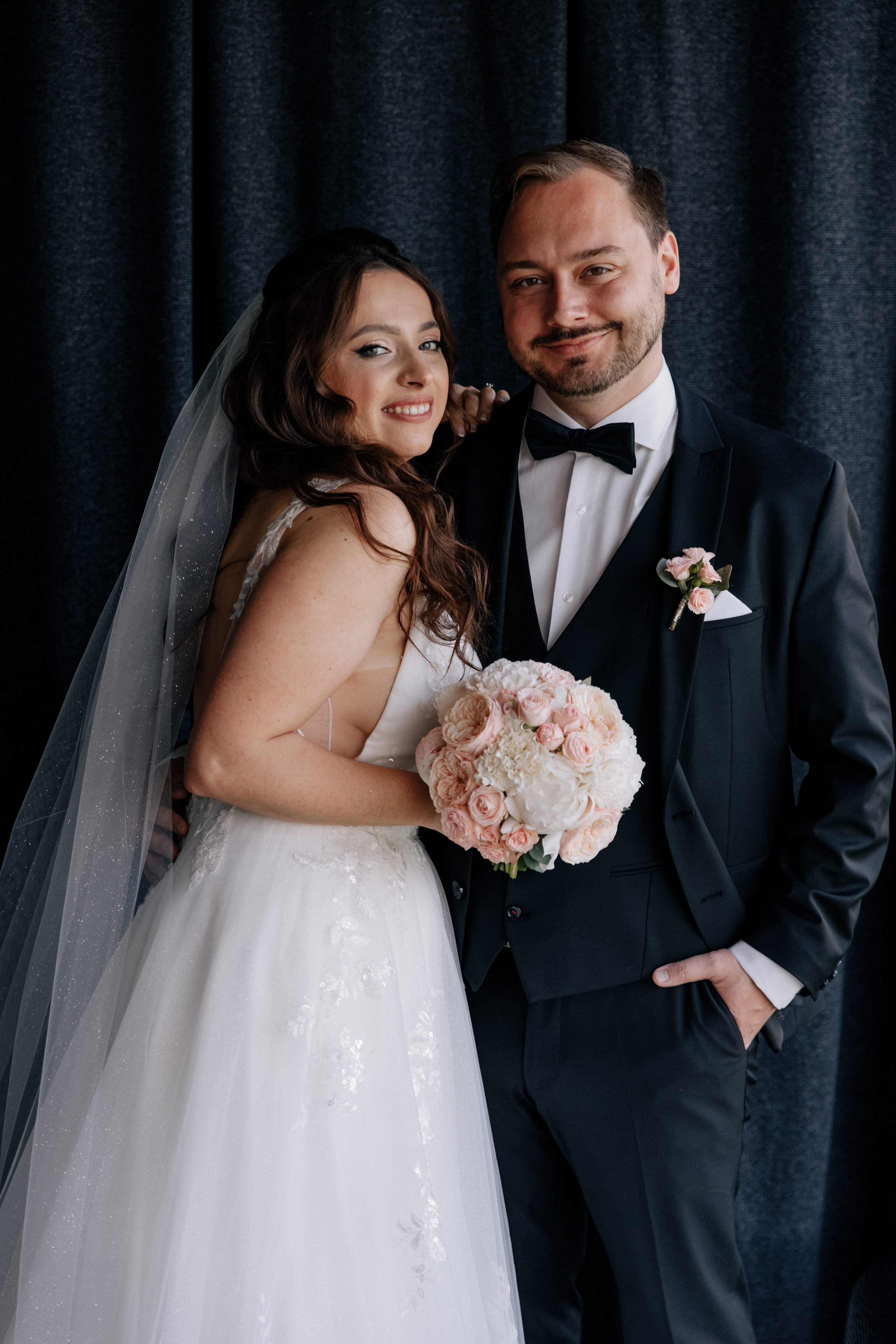 Der Bräutigam und die Braut lächeln glücklich in die Kamera.