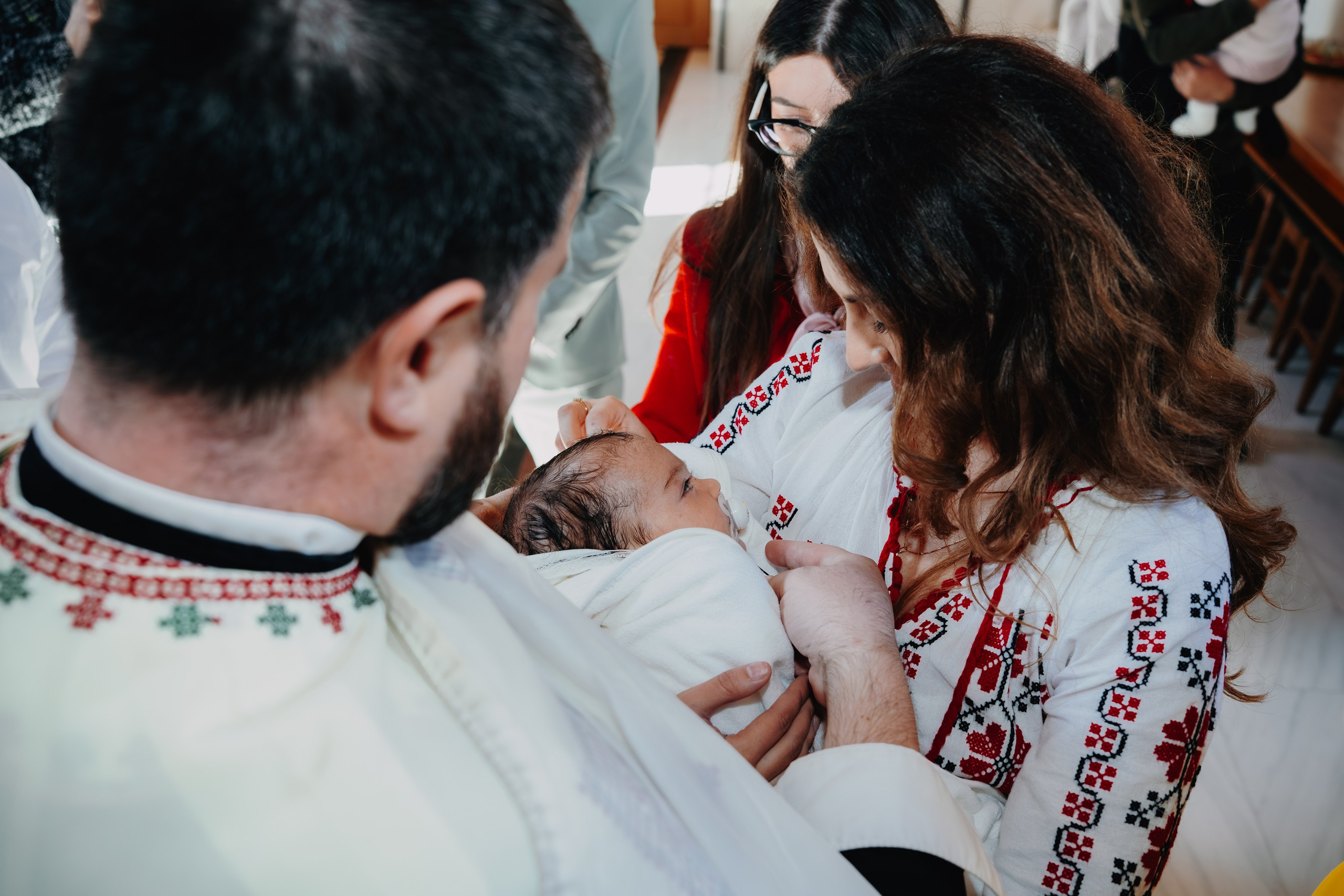 Ritualul încheierii botezului: preotul pune cruciulița sfântă la gâtul pruncului Arthur Mihail, acum îmbrăcat în haine noi și înfășat în prosop. Un moment de binecuvântare finală și simbolism profund.