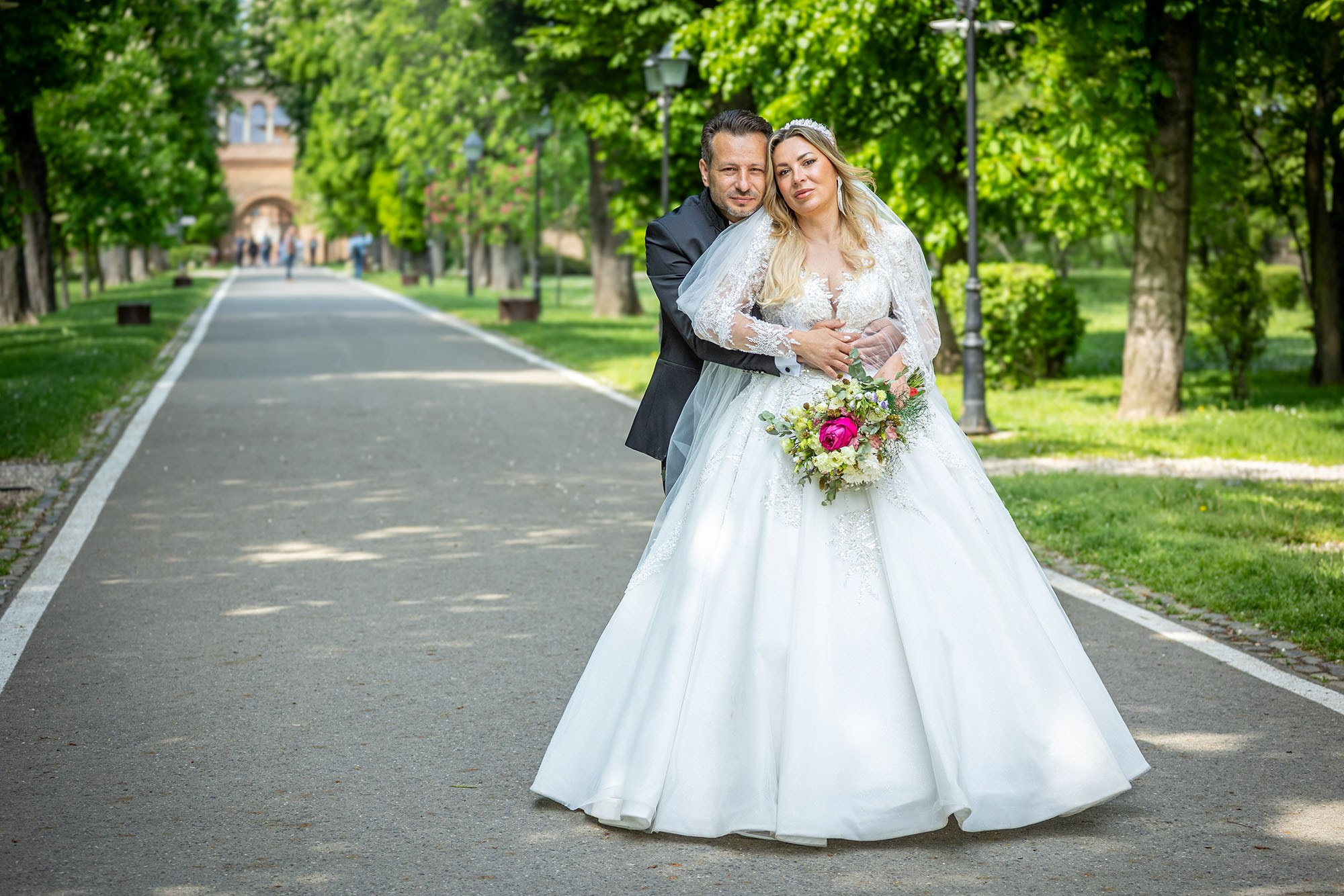 ședință foto nuntă romantică în parc, cuplu elegant, la palat Mireasa și mirele pozând pe aleea cu copaci verzi, sesiune foto nuntă