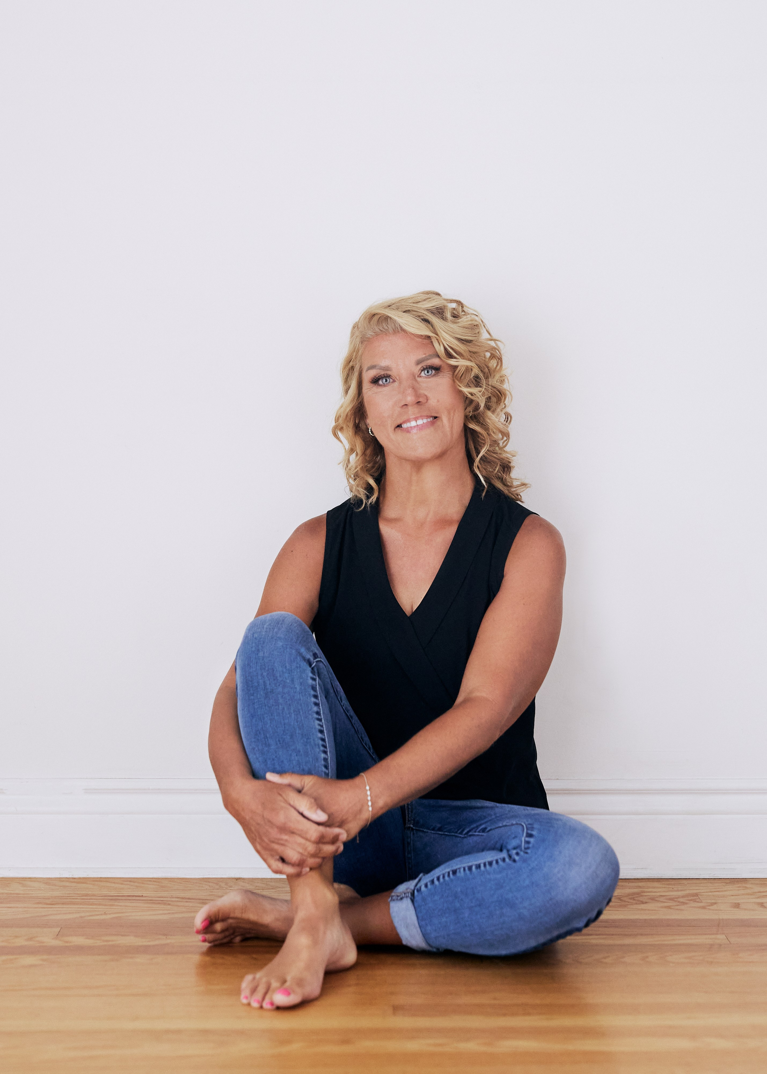 older woman sitting on floor in jeans 