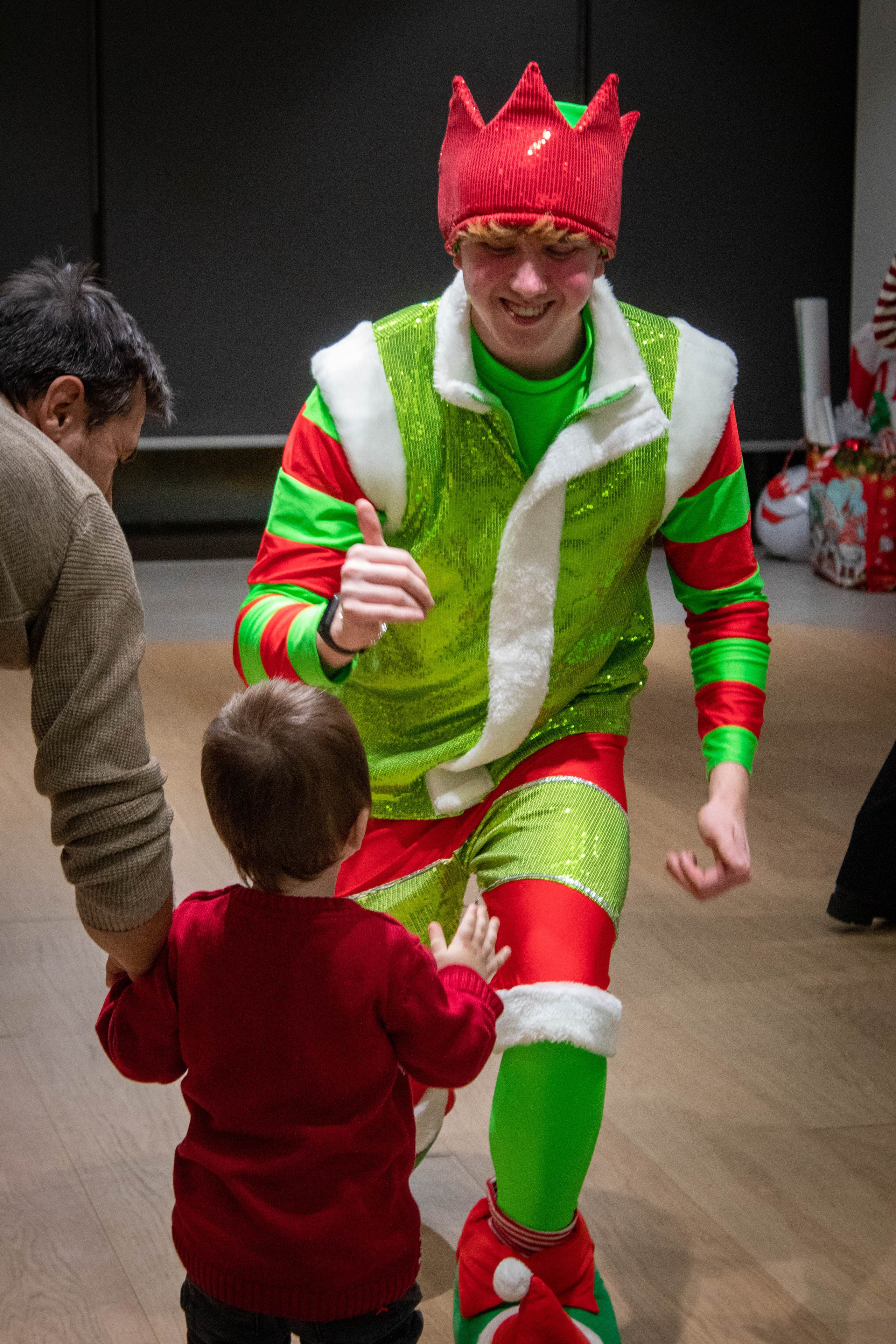 Colorfully dressed elf interacting with a child during a lively celebration.