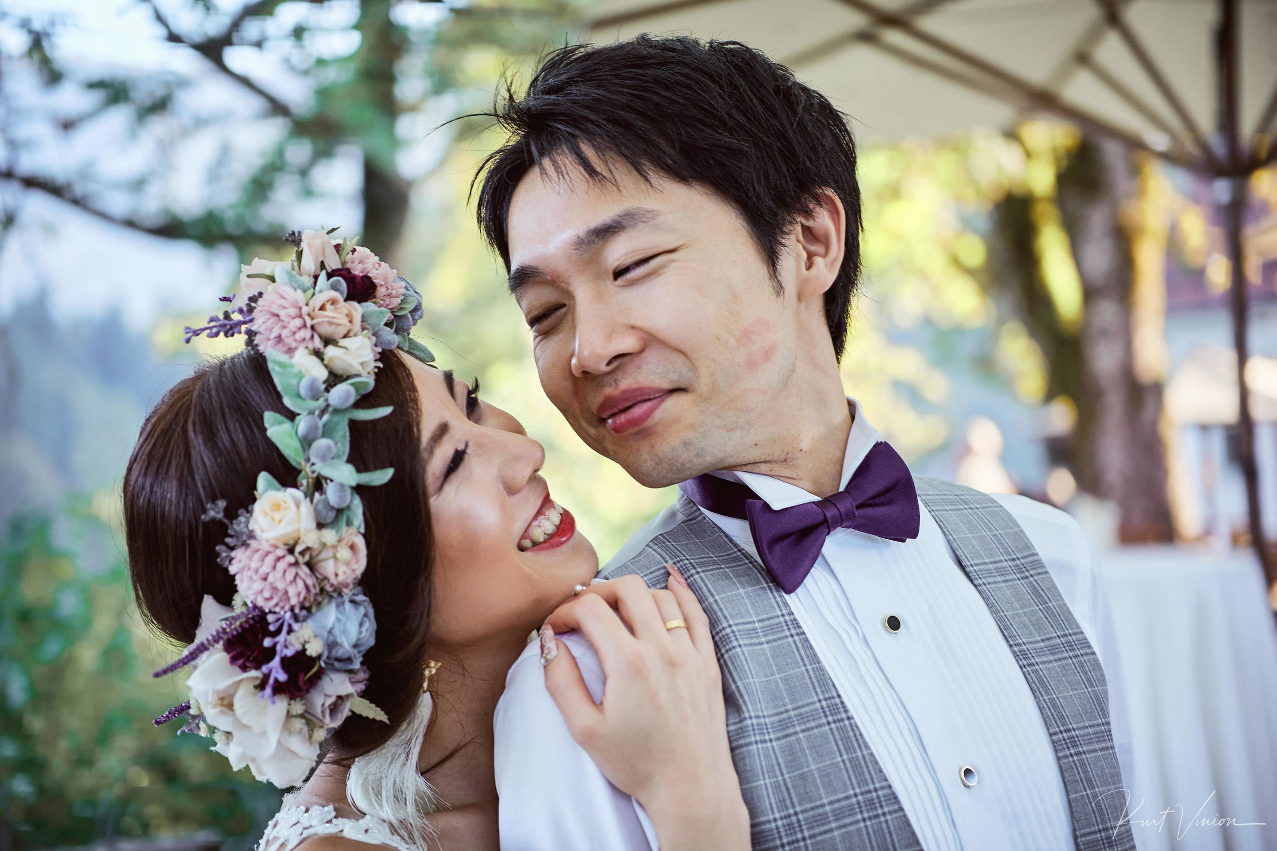 Bride laughing embracing groom from behind post-ceremony portrait.