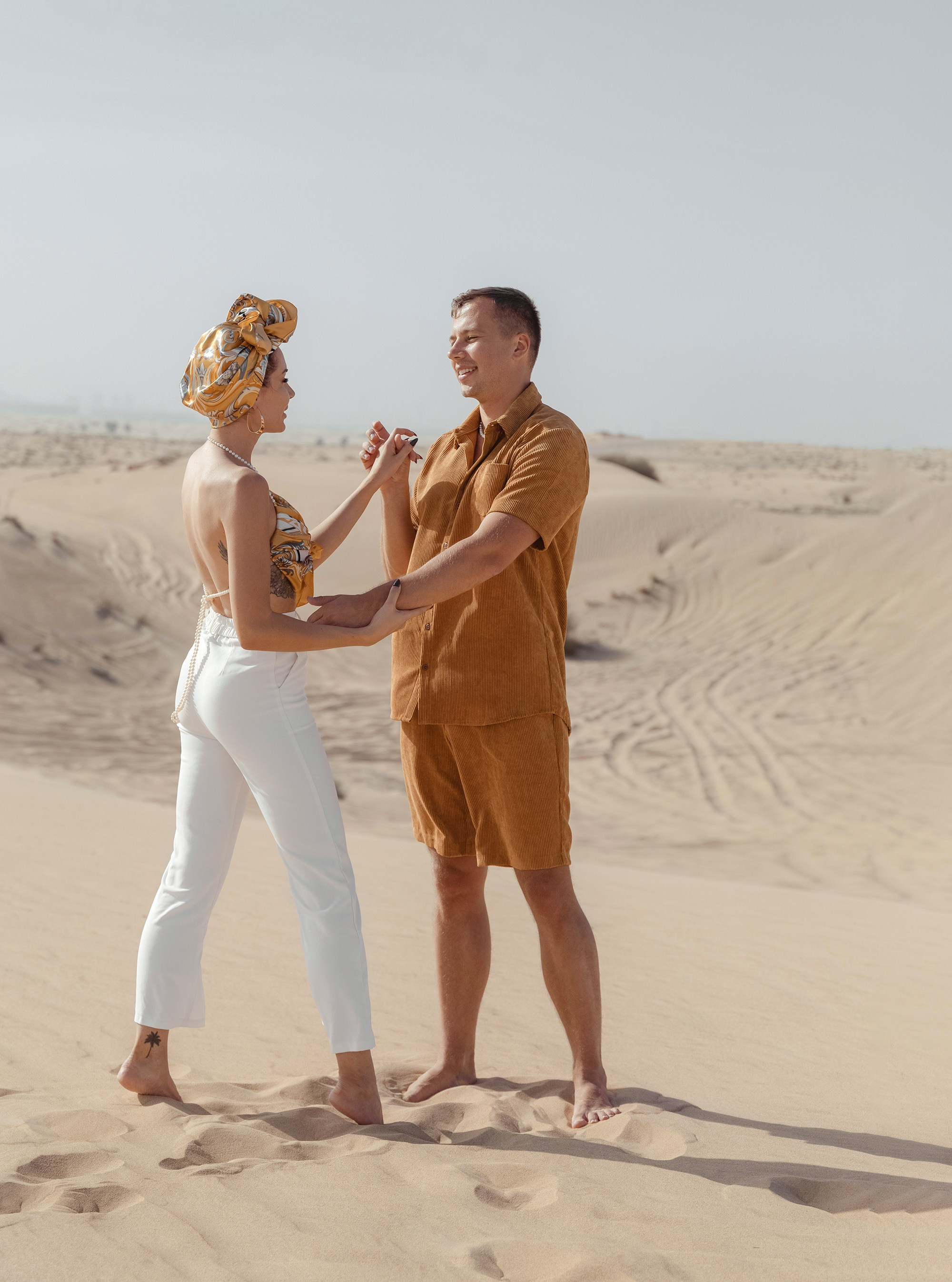 A couple shares a spontaneous, joyful moment in the desert, their embrace reflecting the warmth and beauty of the surrounding nature. Dubai, United Arab Emirates