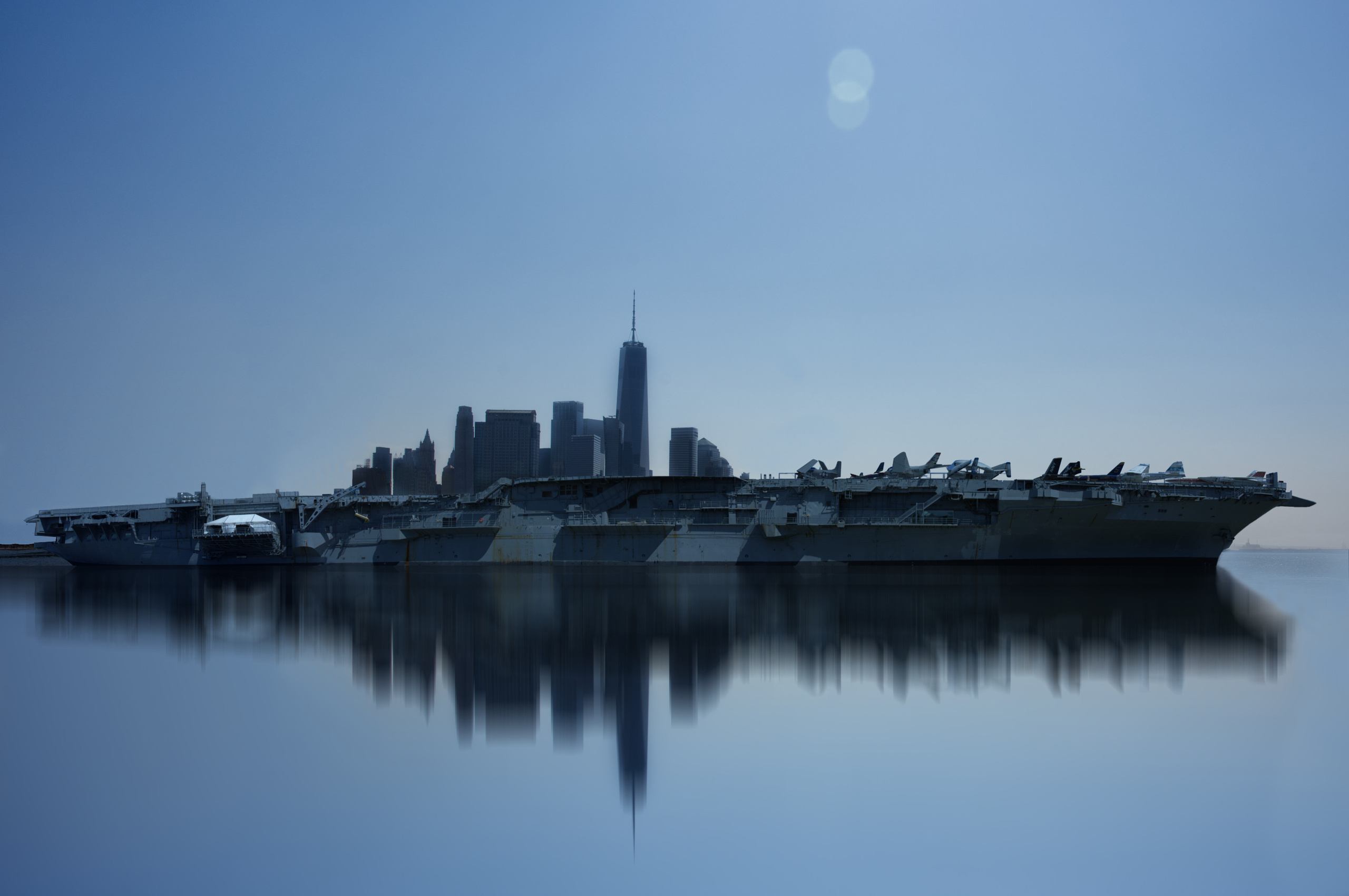 Intrepid, a famous aircraft carrier from the past, majestically combined with the towering skyscrapers of Lower Manhattan. It's a masterful composition that seamlessly blends two symbols of American might and ingenuity. But there's more to this image than just its technical execution. The juxtaposition of the carrier and the city creates a sense of continuity and interconnectedness, as if the Intrepid is carrying the very essence of New York on its sturdy decks. It's a beautiful tribute to the shared history and identity of this great metropolis.