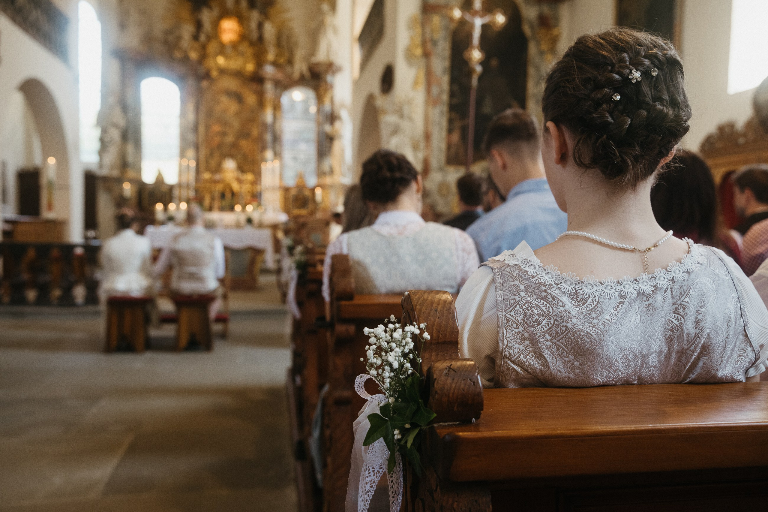 Gäste in Tracht sitzen in Kirche, Hochzeit in Heiligenberg