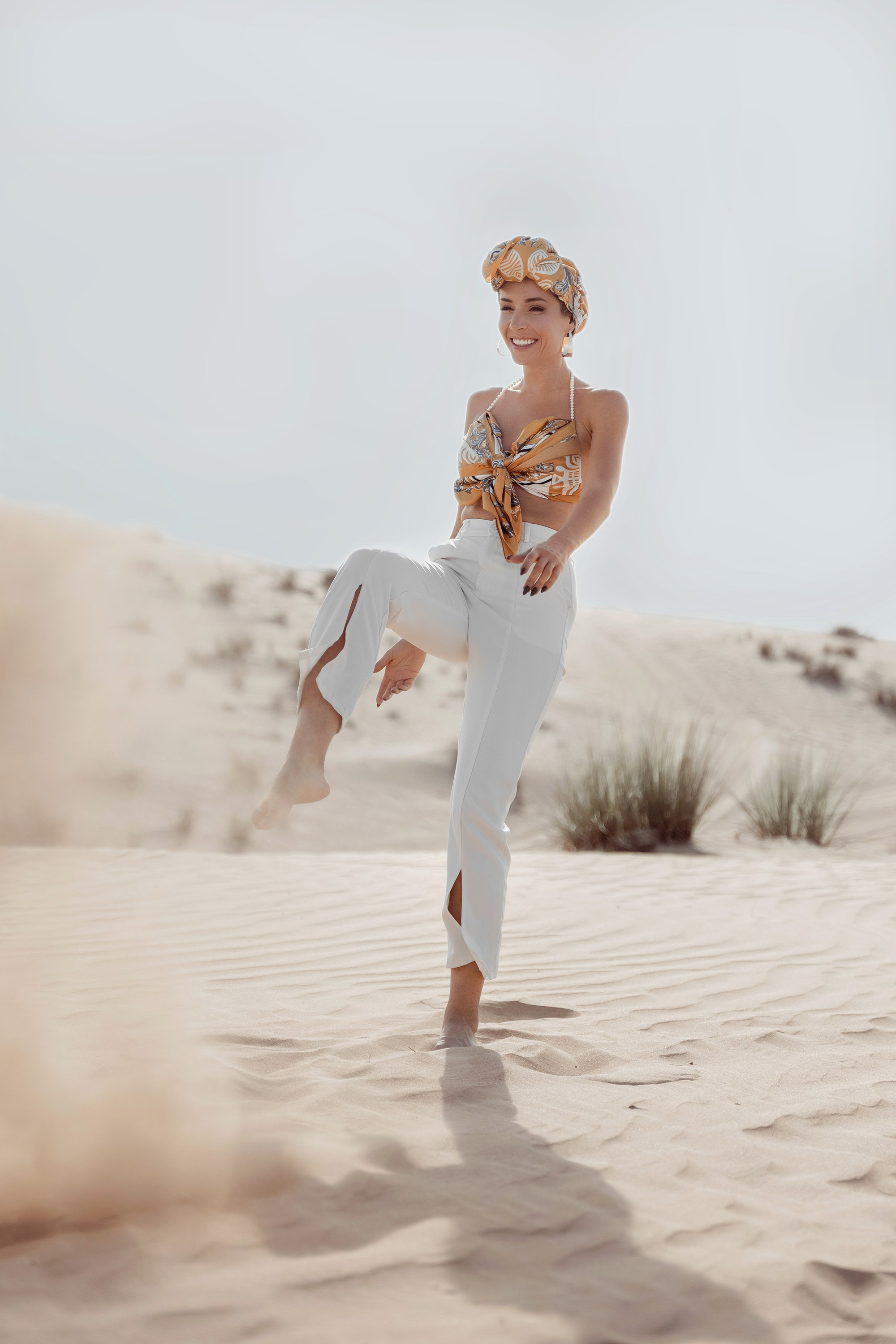 A captivating shot of a woman playing with the sand in the desert. Dubai, United Arab Emirates