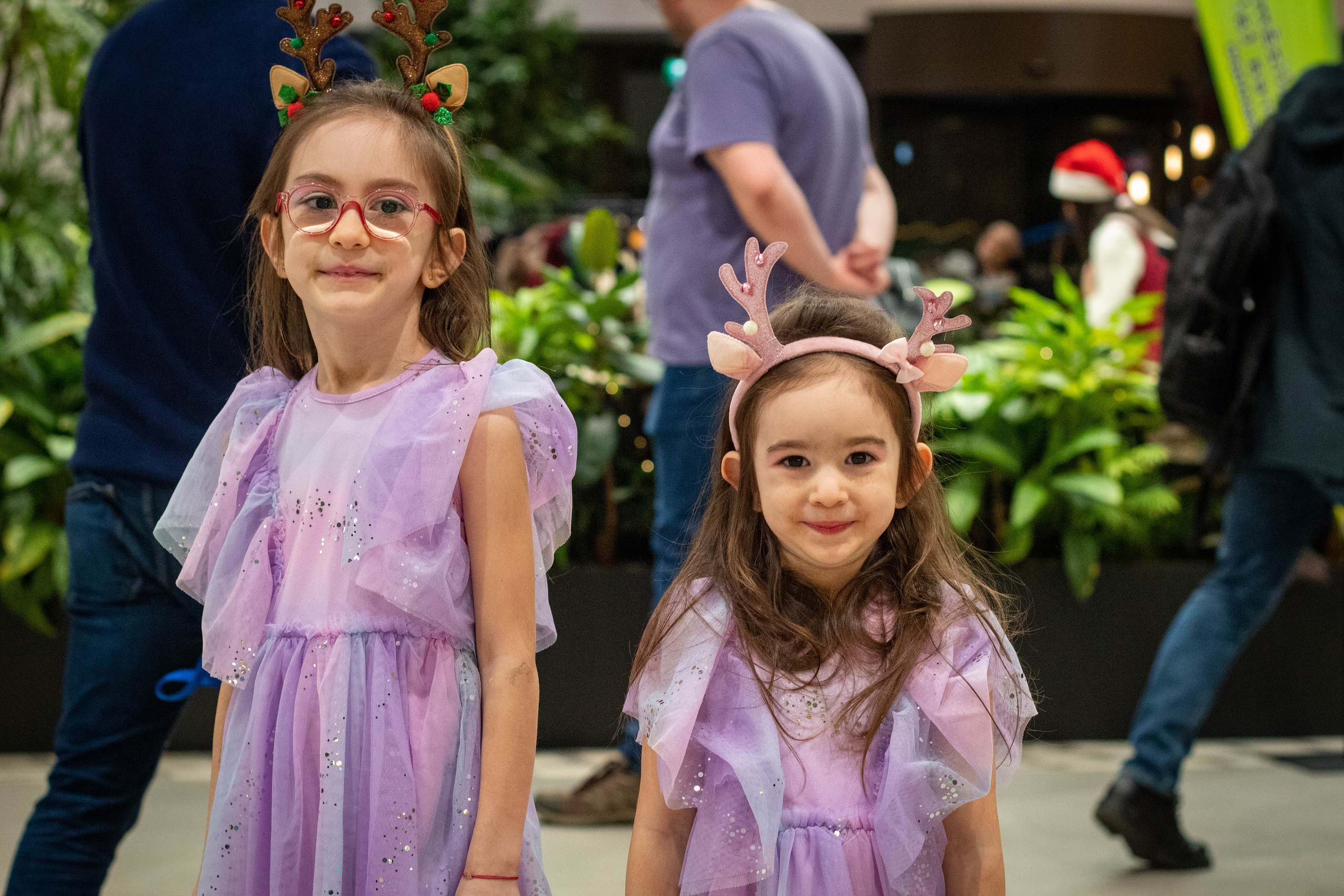 Two young girls laughing and posing together outside in bright daylight.