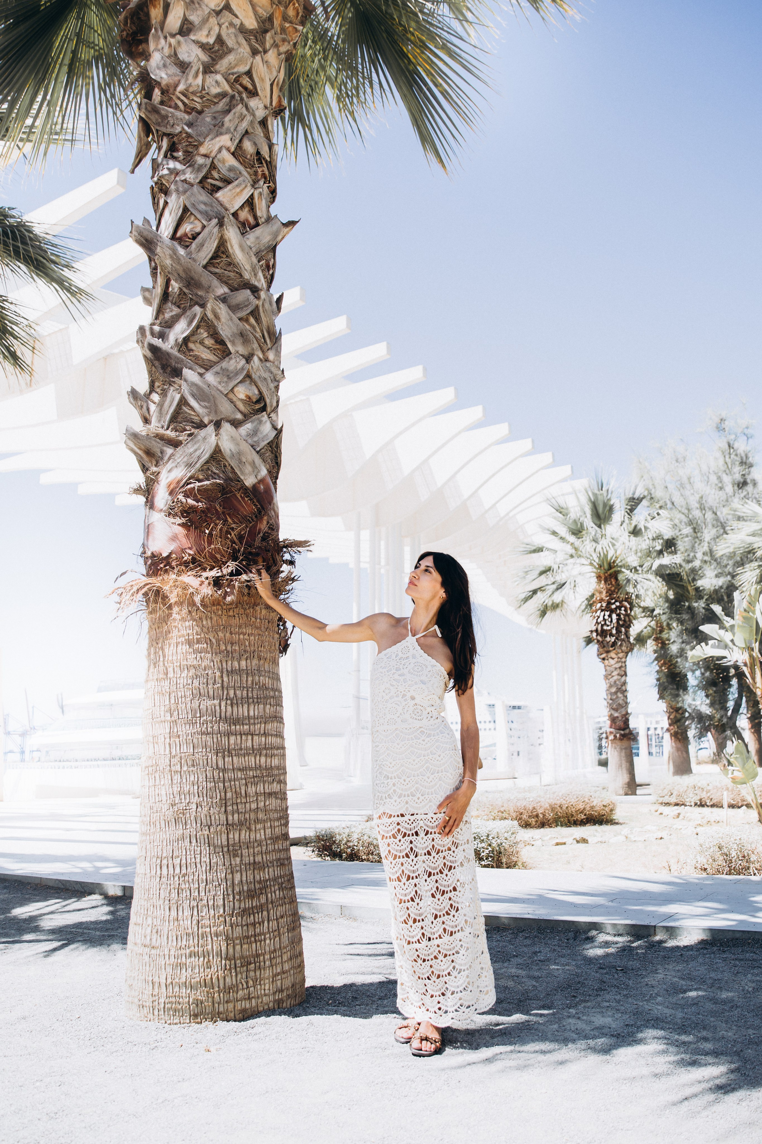 Элегантный уличный портрет женщины в белом летнем платье у пальмы под солнцем в Малаге, Испания — идеальный выбор для тех, кто ищет естественные, вдохновлённые пляжем фотосессии в Малаге и южной Испании.