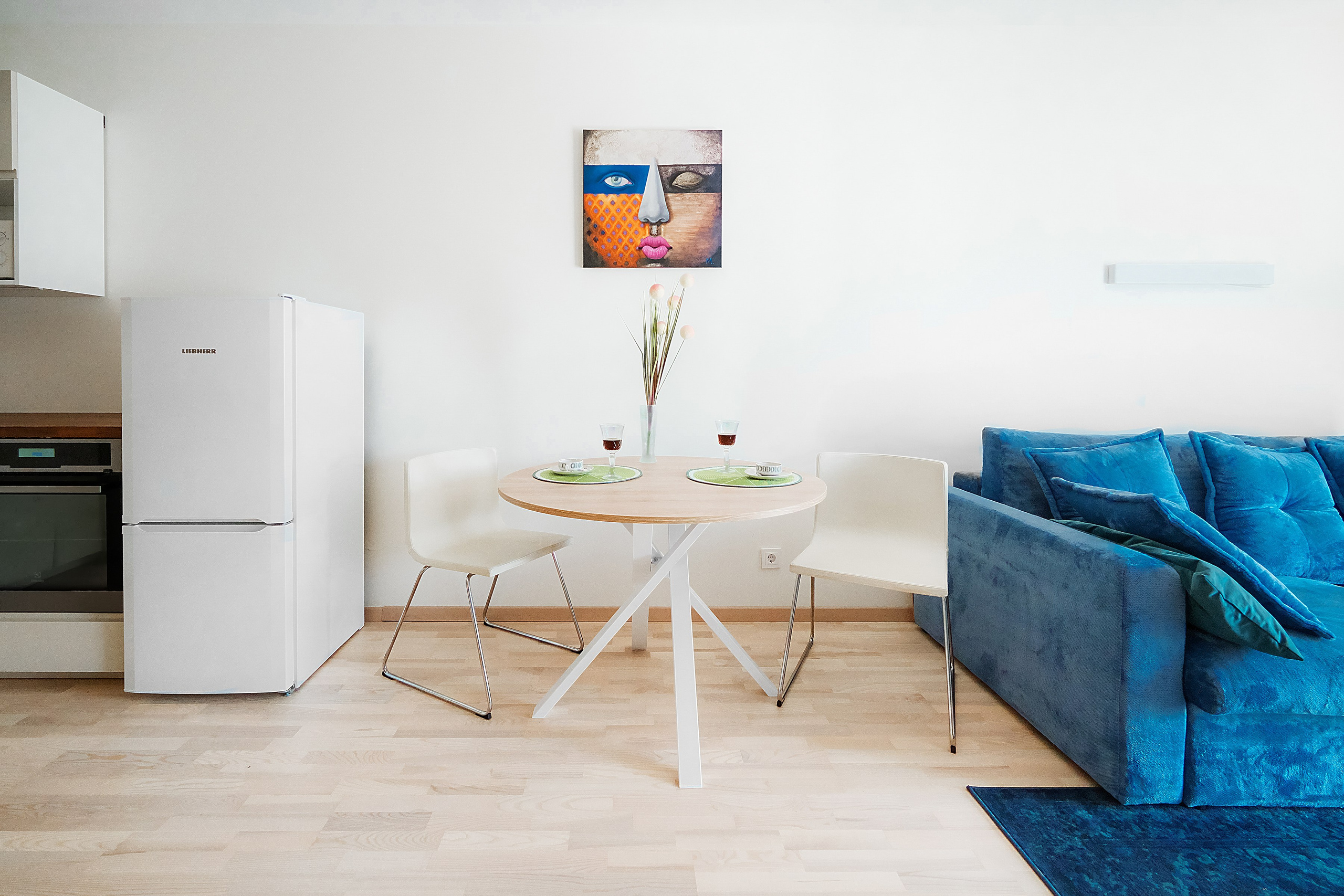 Svetainės interjeras su apvaliu valgomojo stalu ir mėlyna sofa, profesionalus interjero fotografavimas – sapiegafoto.lt