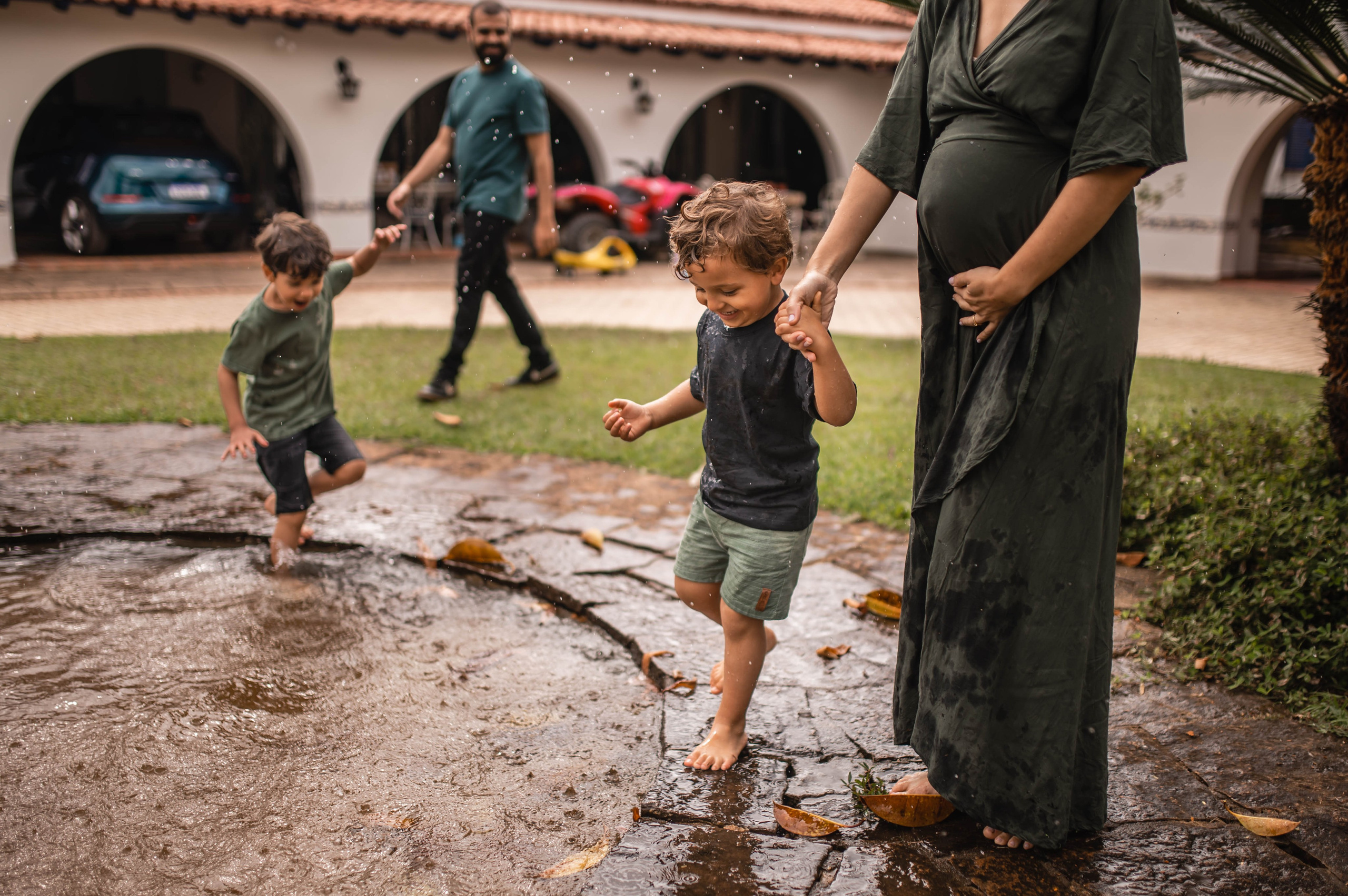 Ensaio gestante lifestyle em Juiz de Fora, filhos brincando na chuva com mãe grávida ao lado