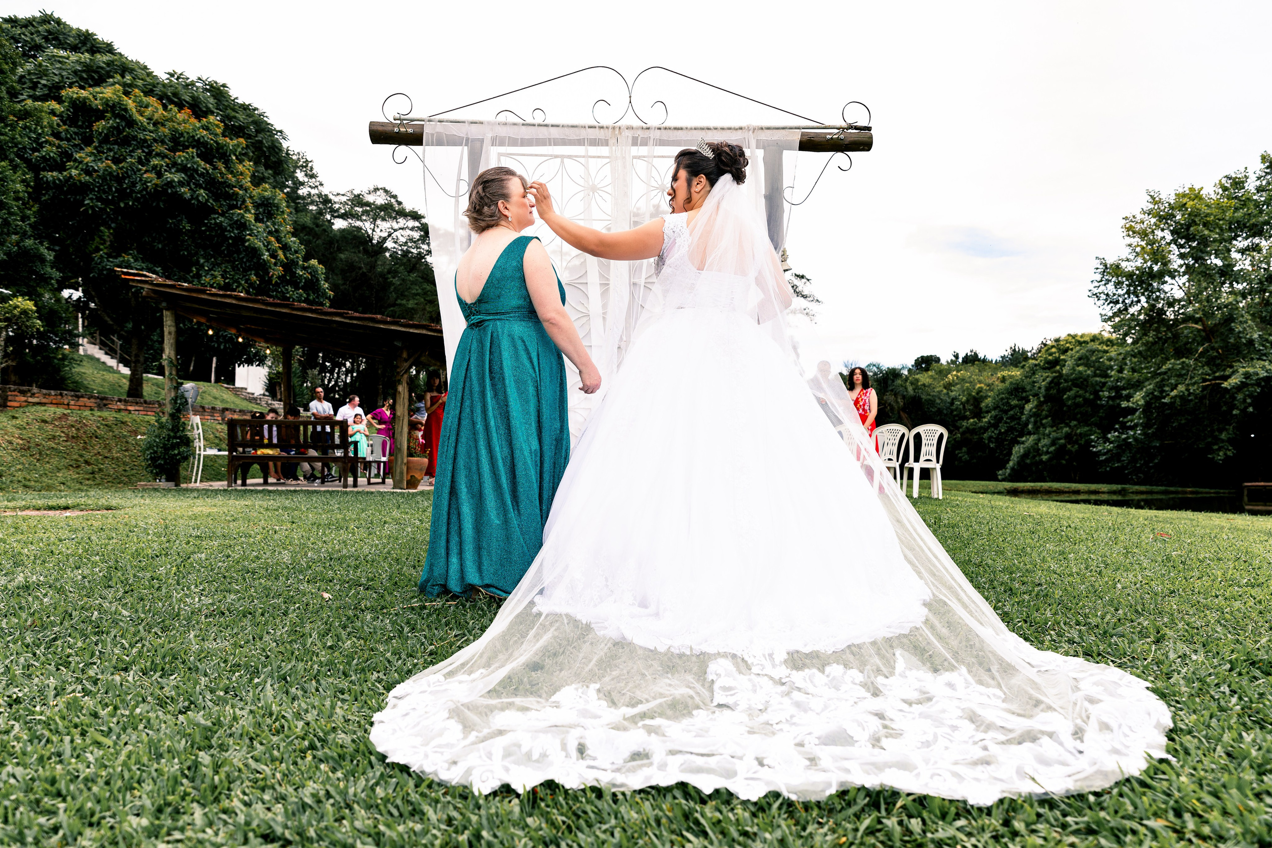 Noiva e mãe de mãos dadas na entrada do altar, união e apoio materno no início da cerimônia.