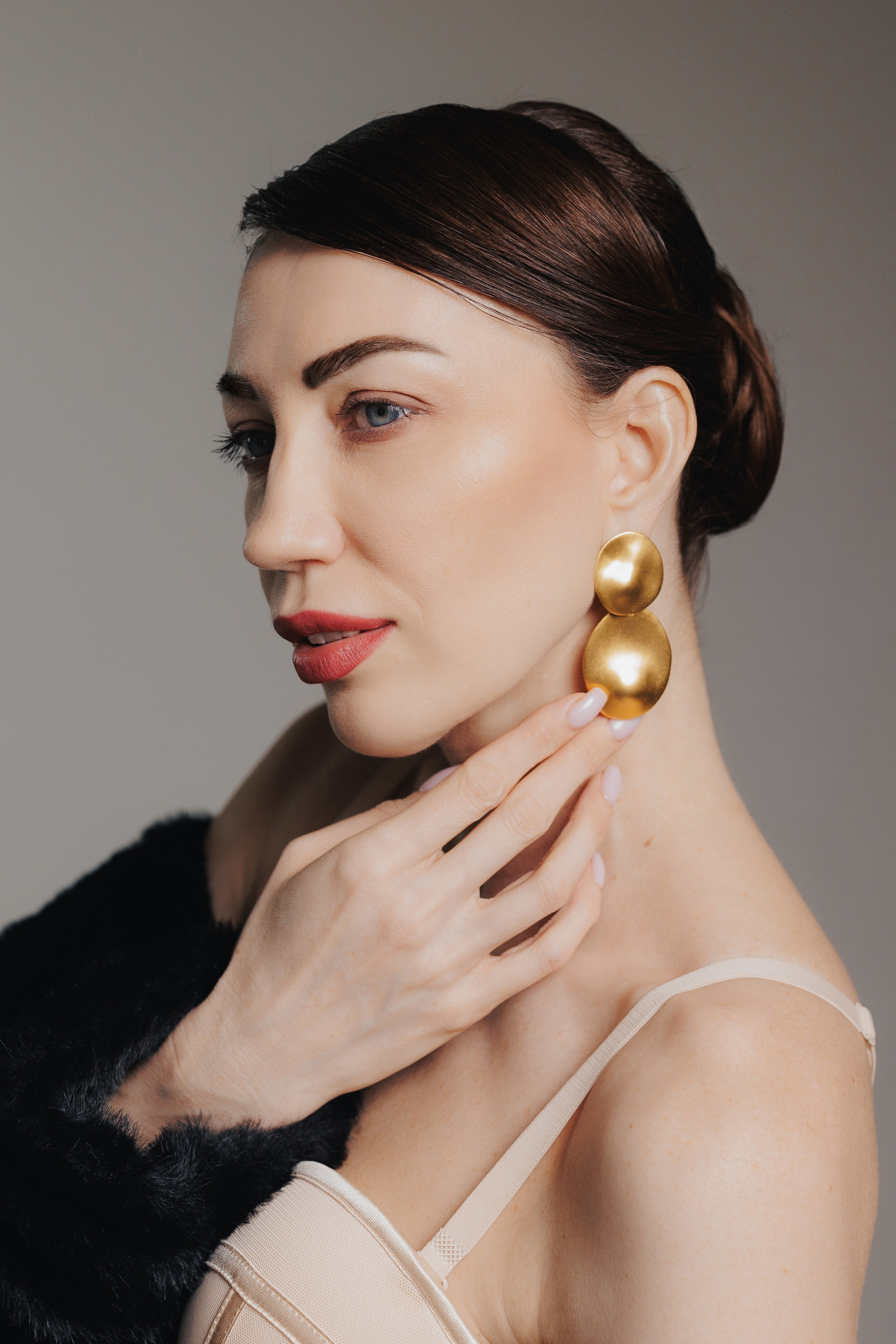 Editorial close-up portrait of an elegant woman with statement earrings and sleek hairstyle in soft studio lighting, photographed in Leipzig, Germany. Крупный редакционный портрет элегантной женщины с выразительными серьгами и гладкой прической в мягком студийном свете, снятый в Лейпциге, Германия.