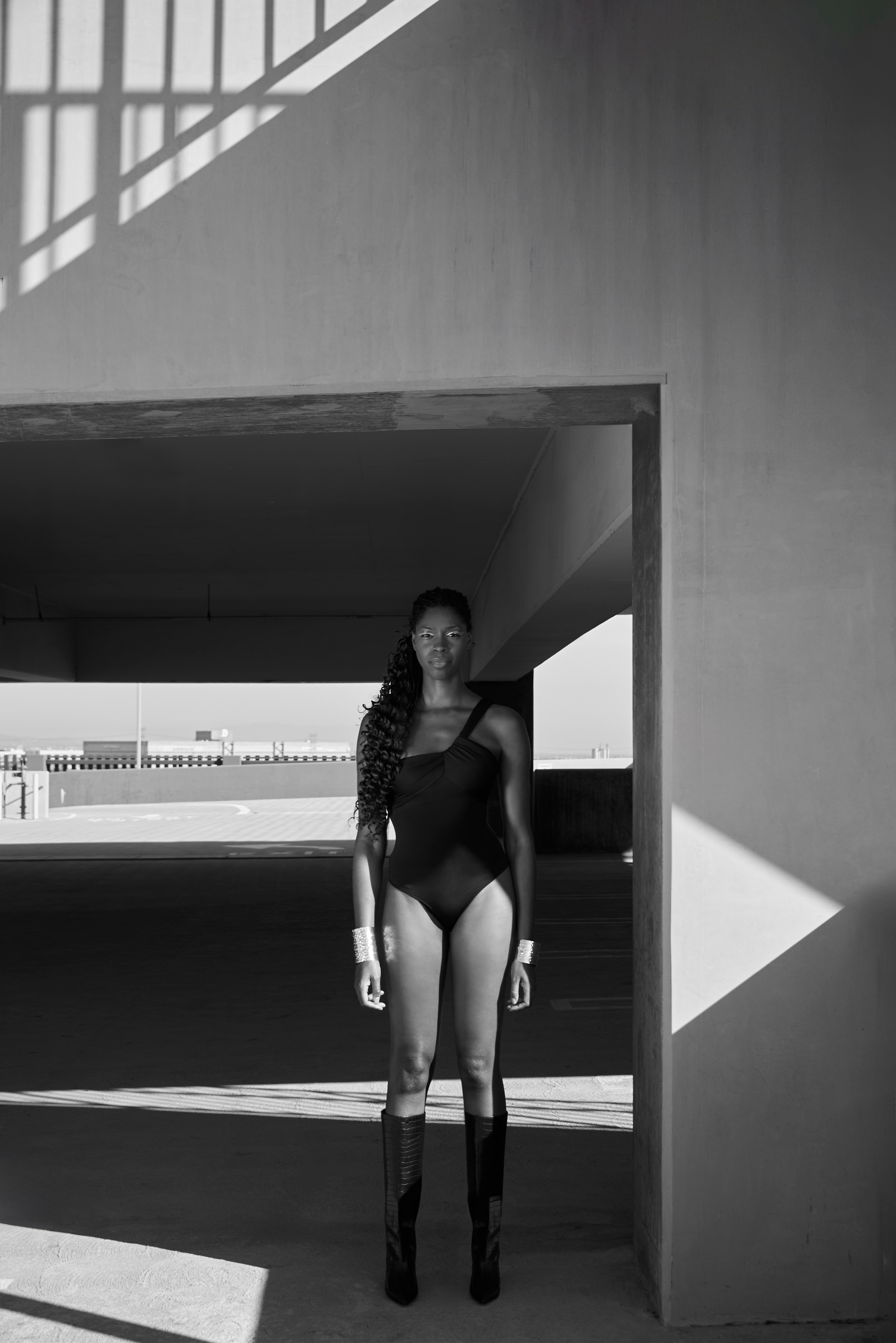 Woman in high boots standing confidently under strong sunlight