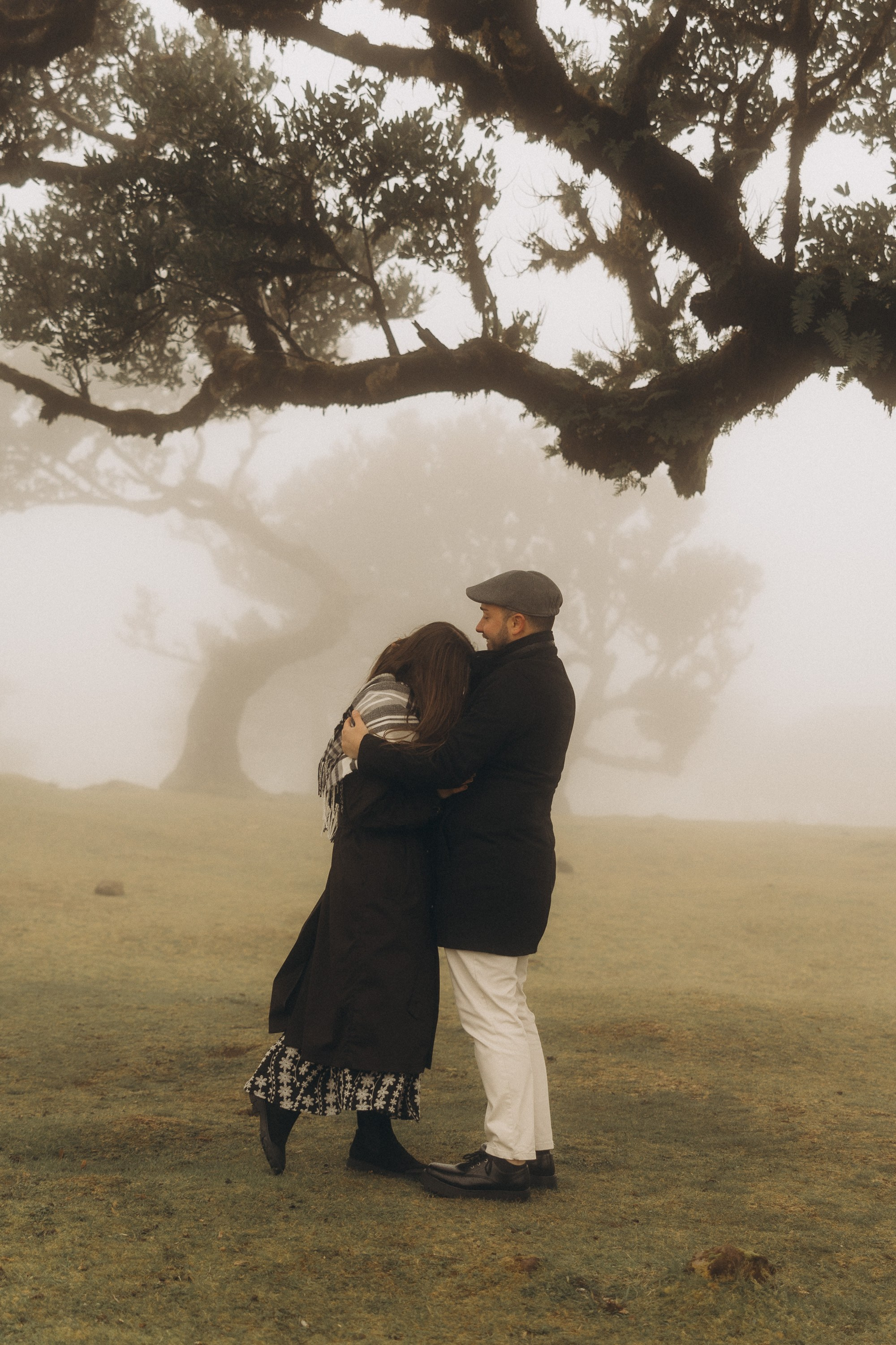 Couple photoshoot in Fanal Forest Madeira PortugalA romantic couple standing amidst the ancient laurel trees of Fanal Forest, Madeira, surrounded by a mystical fog that adds an ethereal touch to the scene
