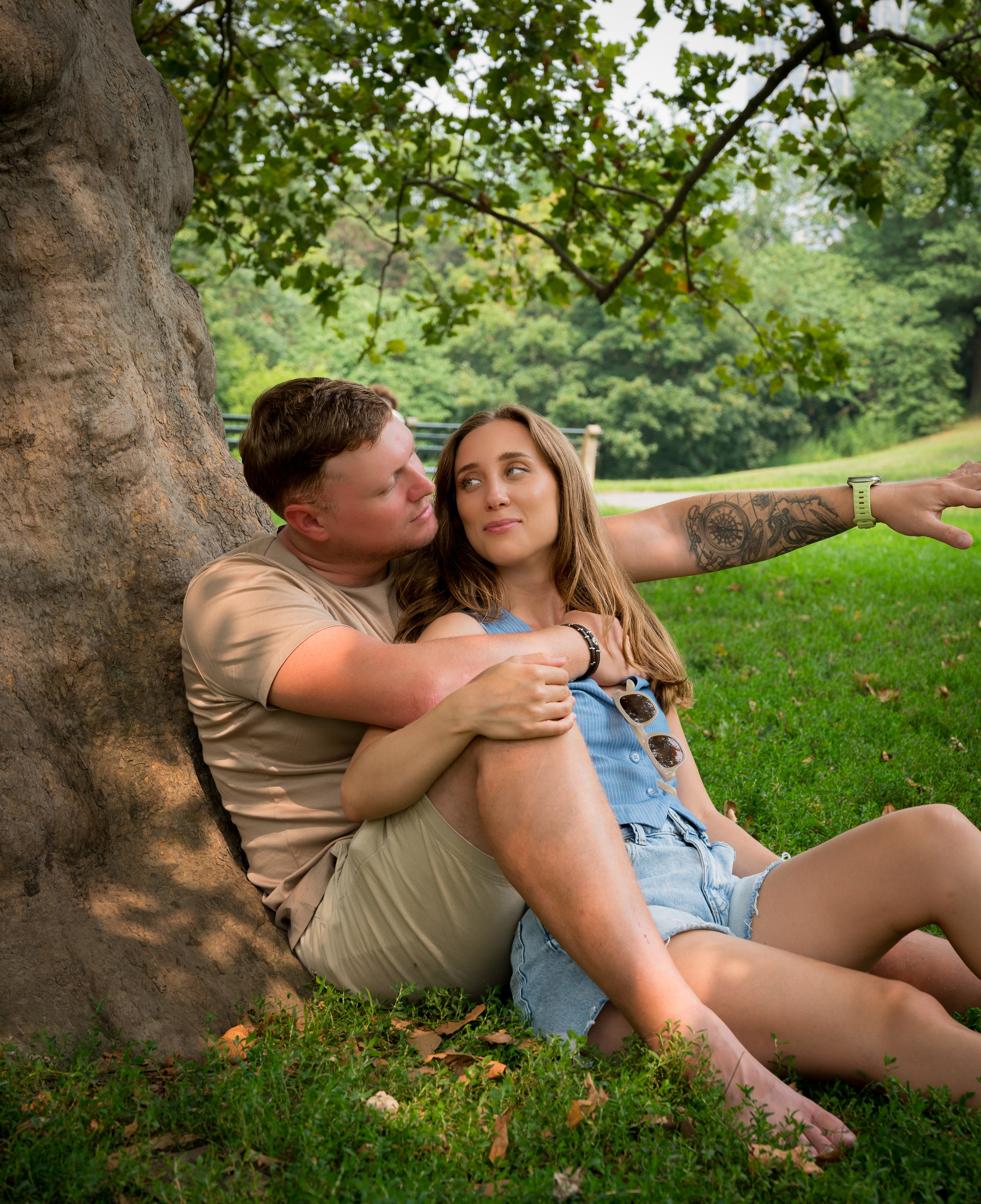 Couple sitting by a large tree in a park, relaxed romantic pose, natural light couple session in New York.